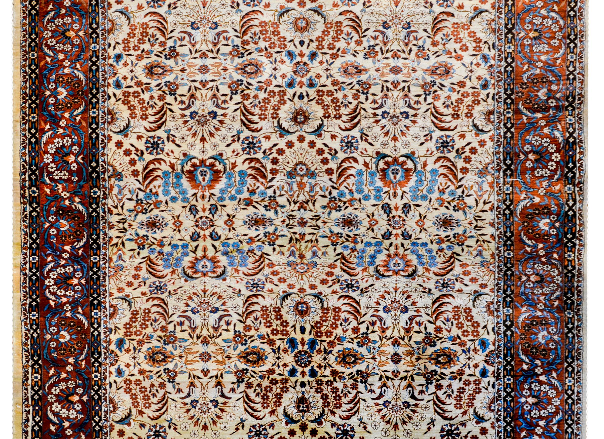 An incredible vintage Chinese silk rug with a beautiful bold floral pattern woven in crimson, rust, light and dark indigo, cream, and white colored vegetable dyed wool. The border is similarly patterned with a wide central floral stripe flanked by