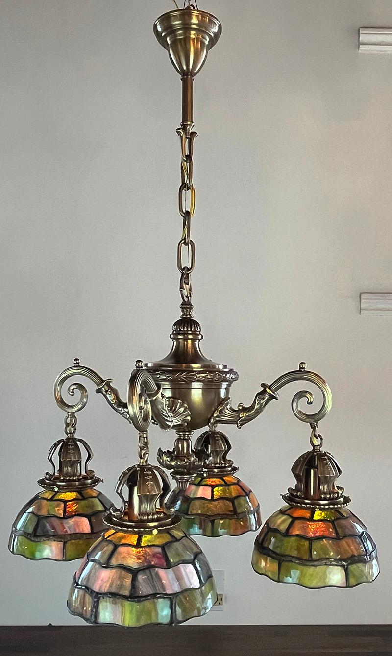 This stunning early 1900s four light is dripping with detail from the heavy cast acanthus finial to the rich cast dolphin arms. A quality fixture in its day (much as it is now) it would have originally hung in a grand home. The leaded glass shades