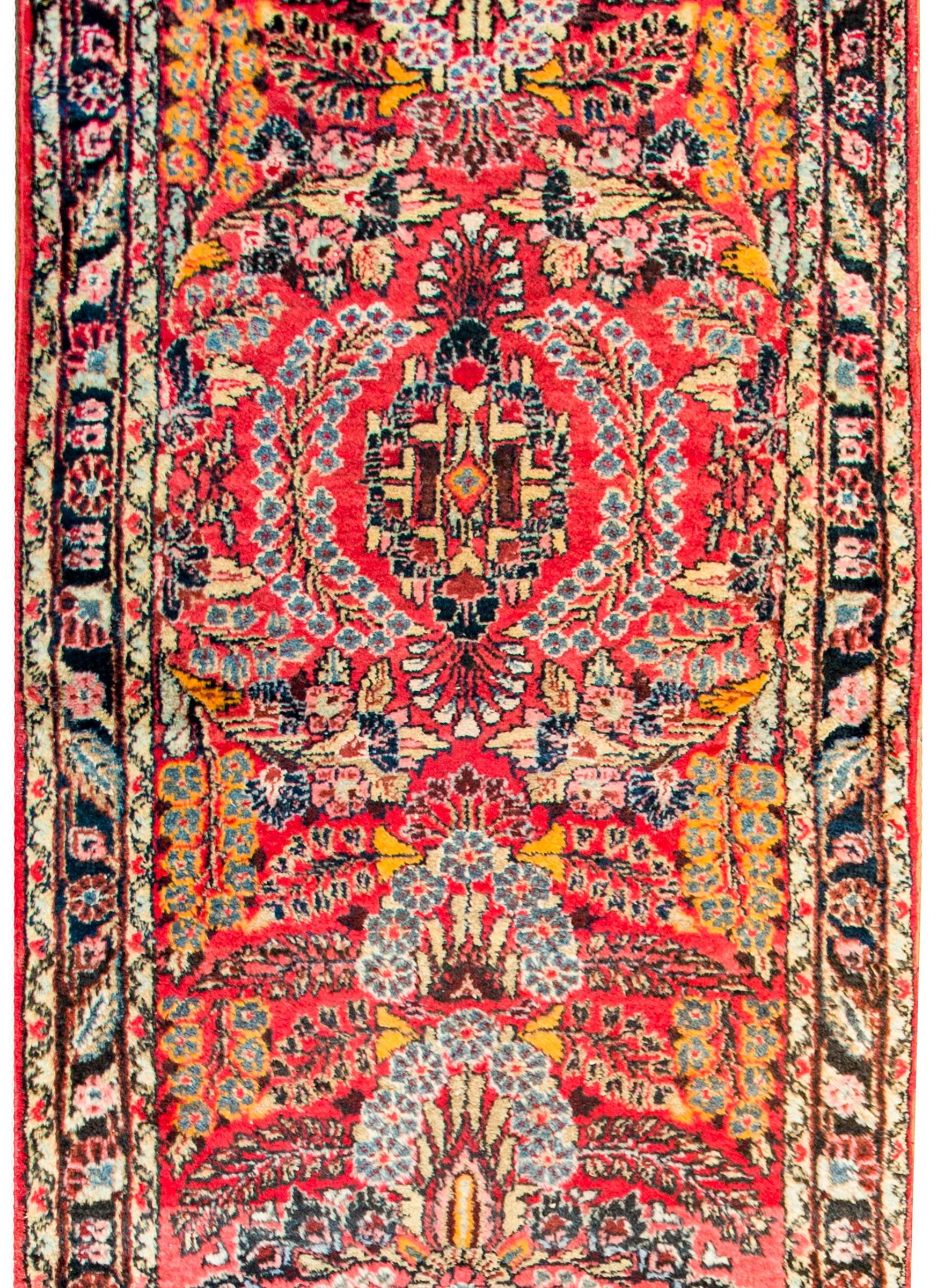 An incredible early 20th century Persian Lilihan runner with a beautiful mirrored floral and leaf patterned motif flanked by a complex border of multiple floral and leaf patterned stripes.