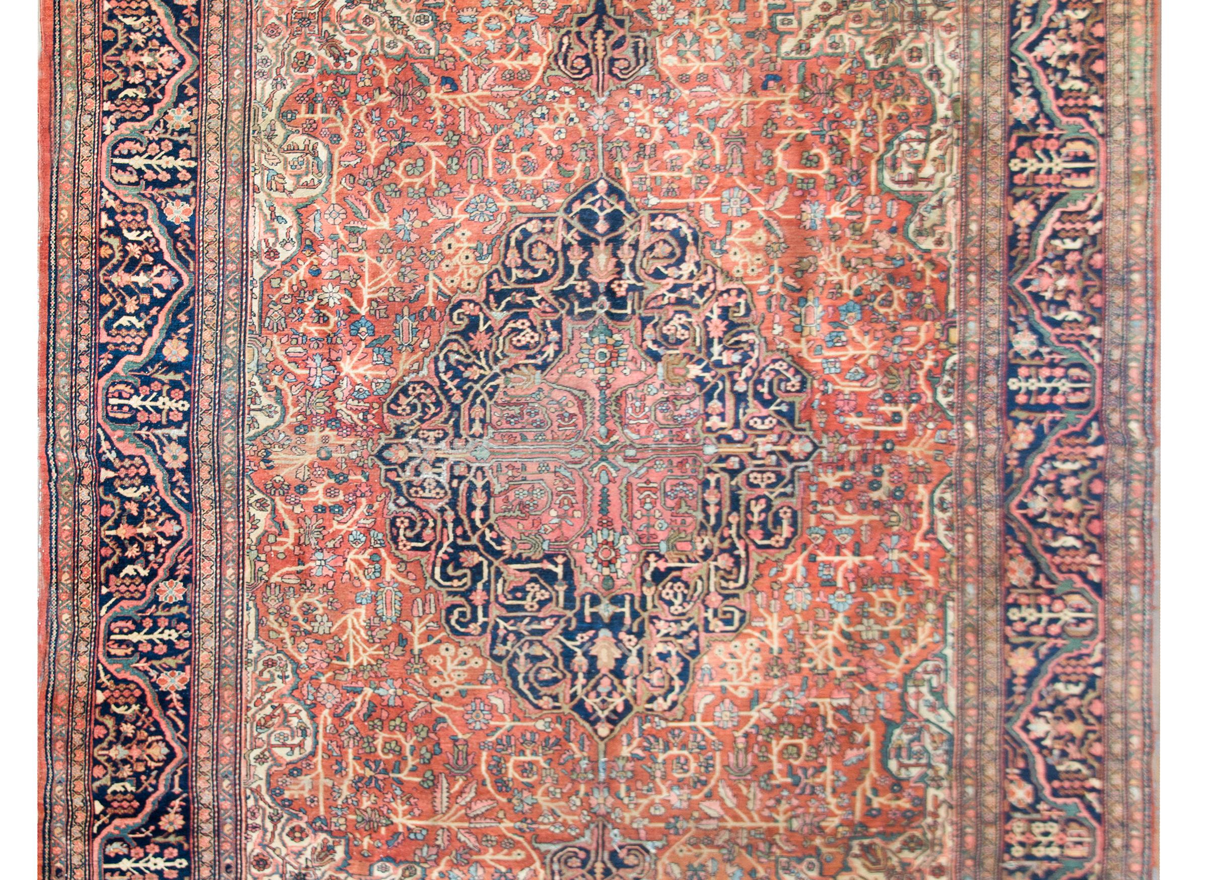 An incredible early 20th century Persian Sarouk rug with the most elaborate central medallion with densely woven scrolling vine and floral pattern woven in myriad colors including coral, light and dark indigo, green and cream, and all set against a