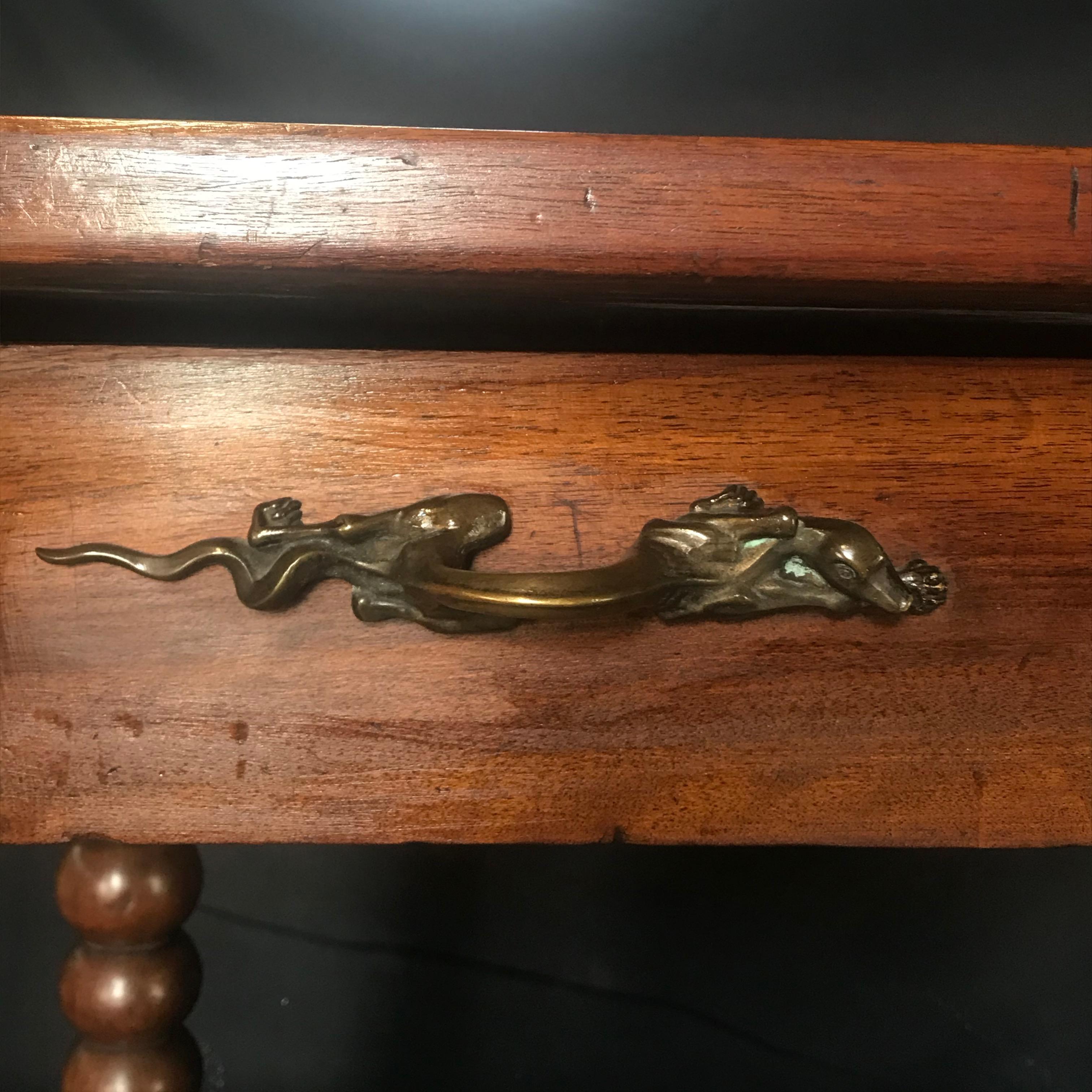 Bought in Lyon, France, this unusual French 19th Century walnut side table has the most unique pulls we have ever seen: beautifully crafted bronze lizard pulls! The size of this versatile early French side table or bedside table with early hand