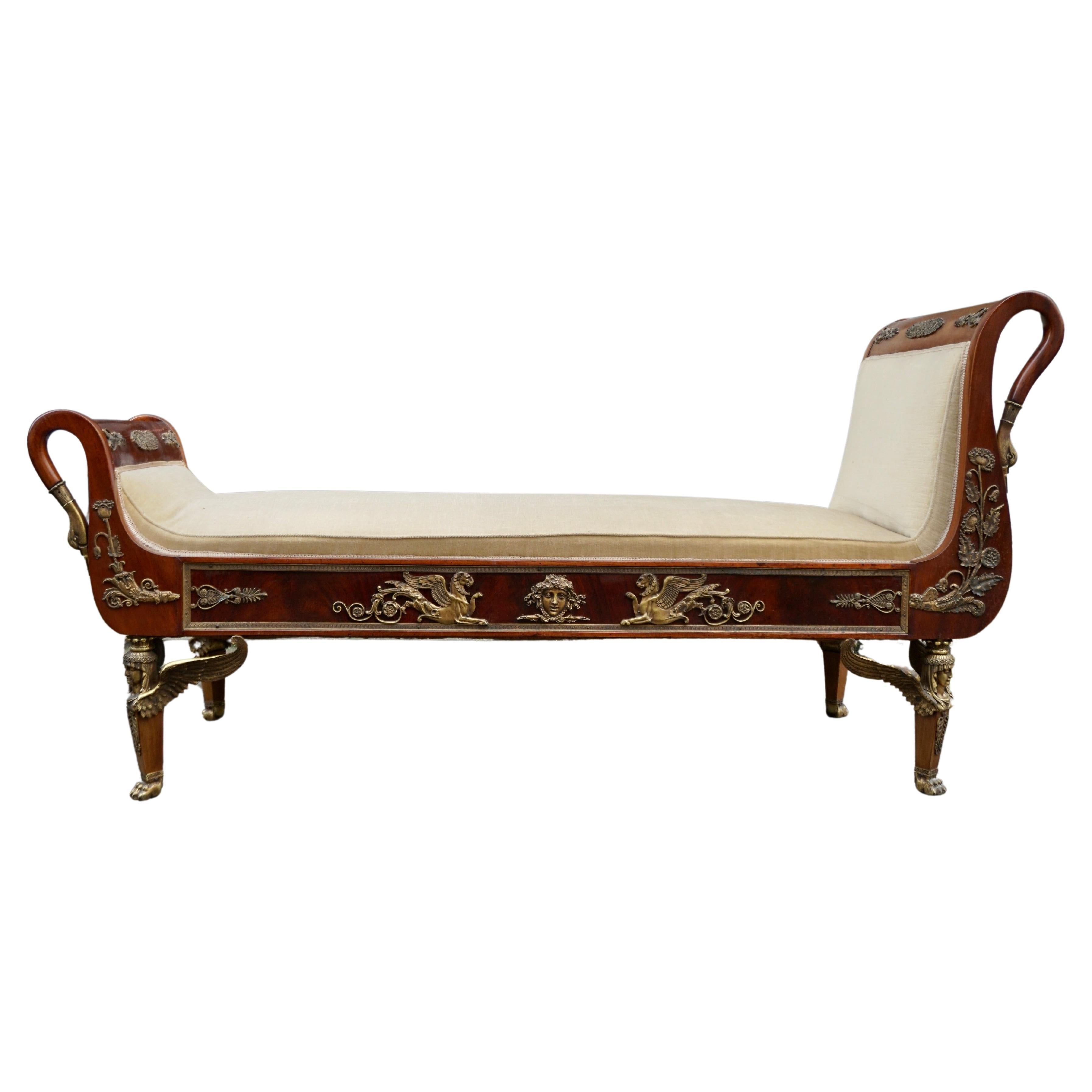 19th century French Empire daybed chaise lounge featuring carved swan neck ends. 

The cushioned seat within padded ends of unequal height with gilded swan- necked facing boards over a panelled apron applied with cast poppies, hippocampi, and Apollo
