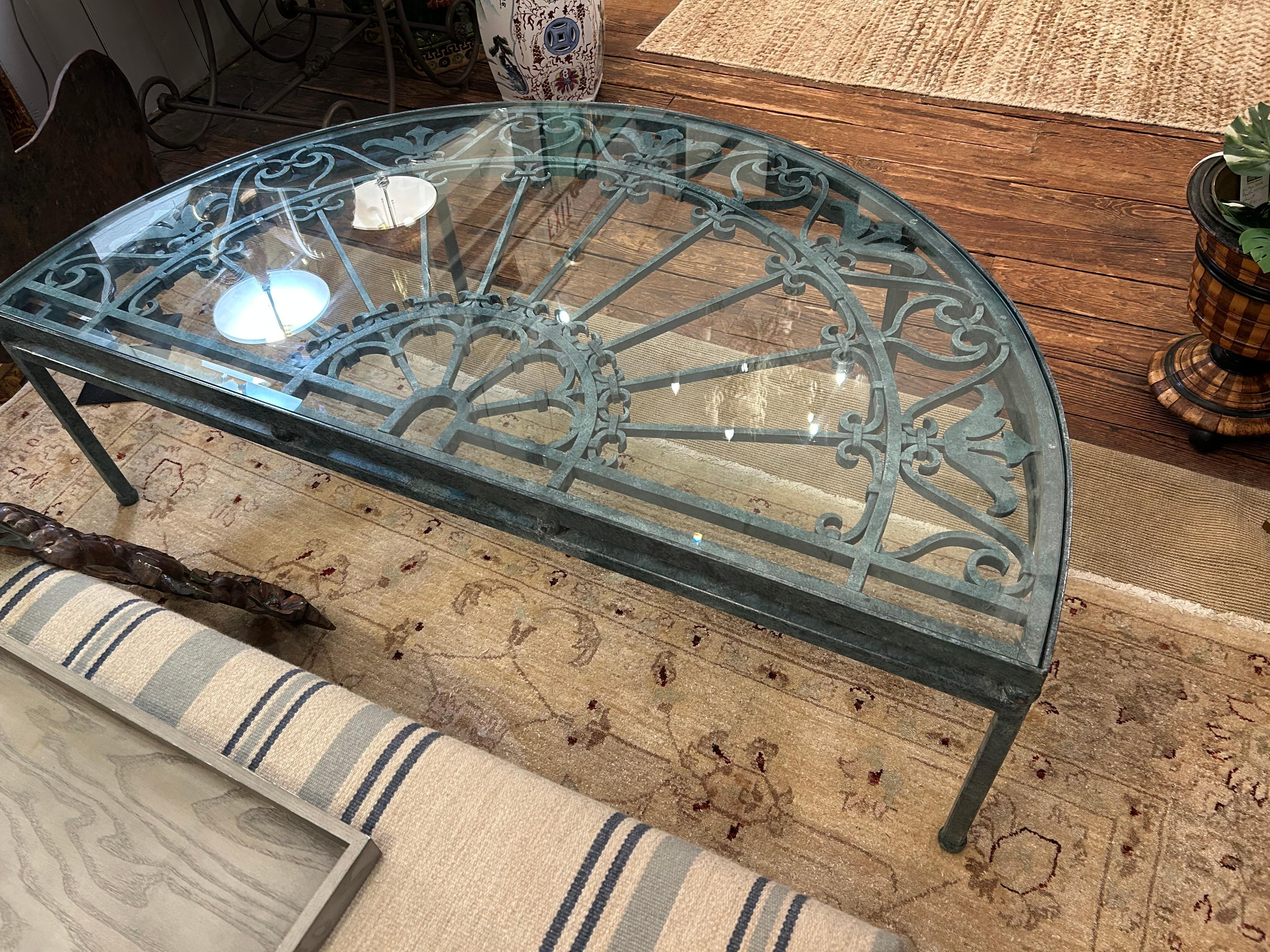 Gorgeous vintage architectural fragment from an iron garden gate, beautifully faux painted and mounted in a matching half moon shaped iron base to create a one of a kind coffee table.  Glass top.