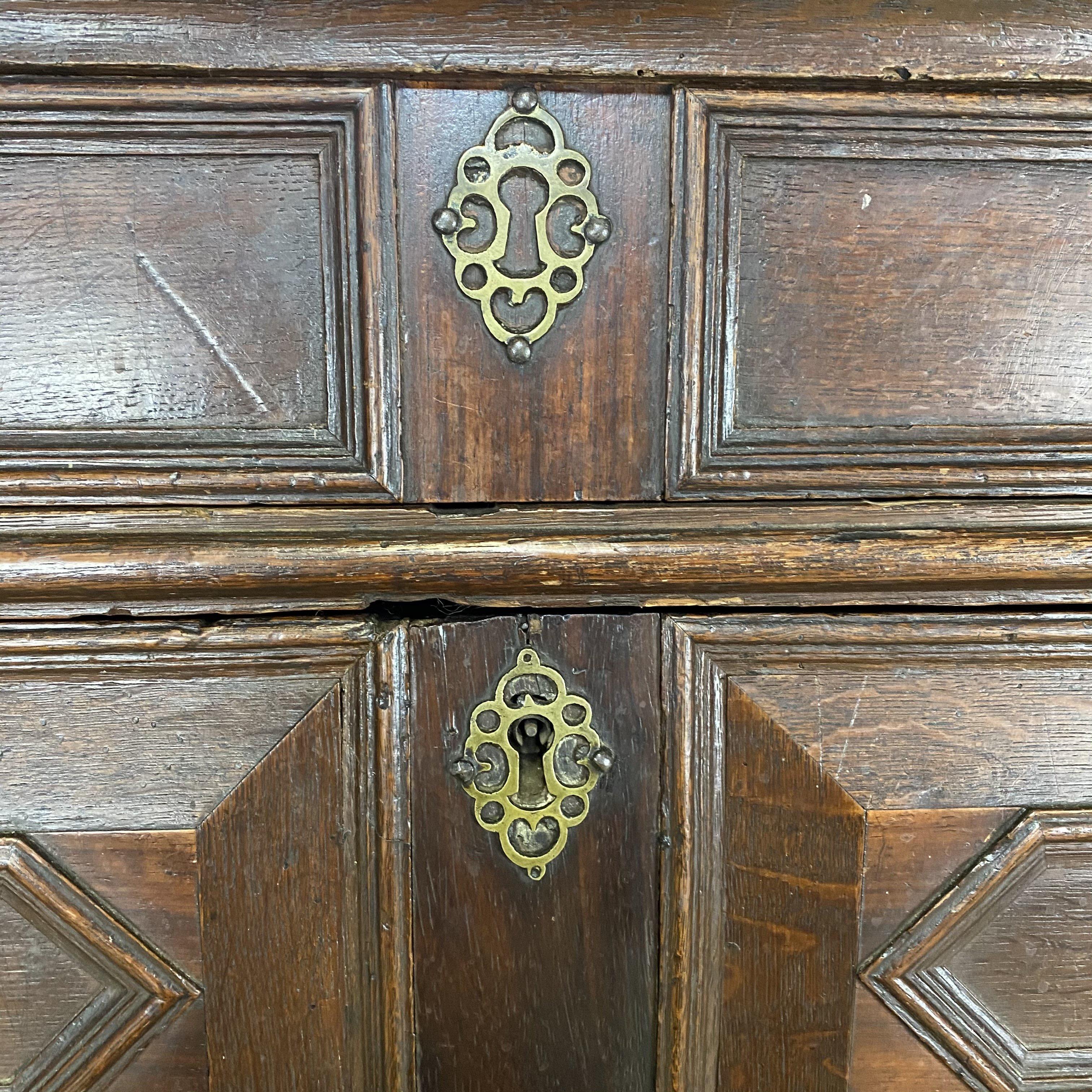 Outstanding 17th century English Charles II oak chest with drawers of varied sizes with bold geometric patterned paneled fronts, paneled sides, brass teardrop pulls, raised on carved bracket feet. Perfect as an entry hall chest, night stand, or