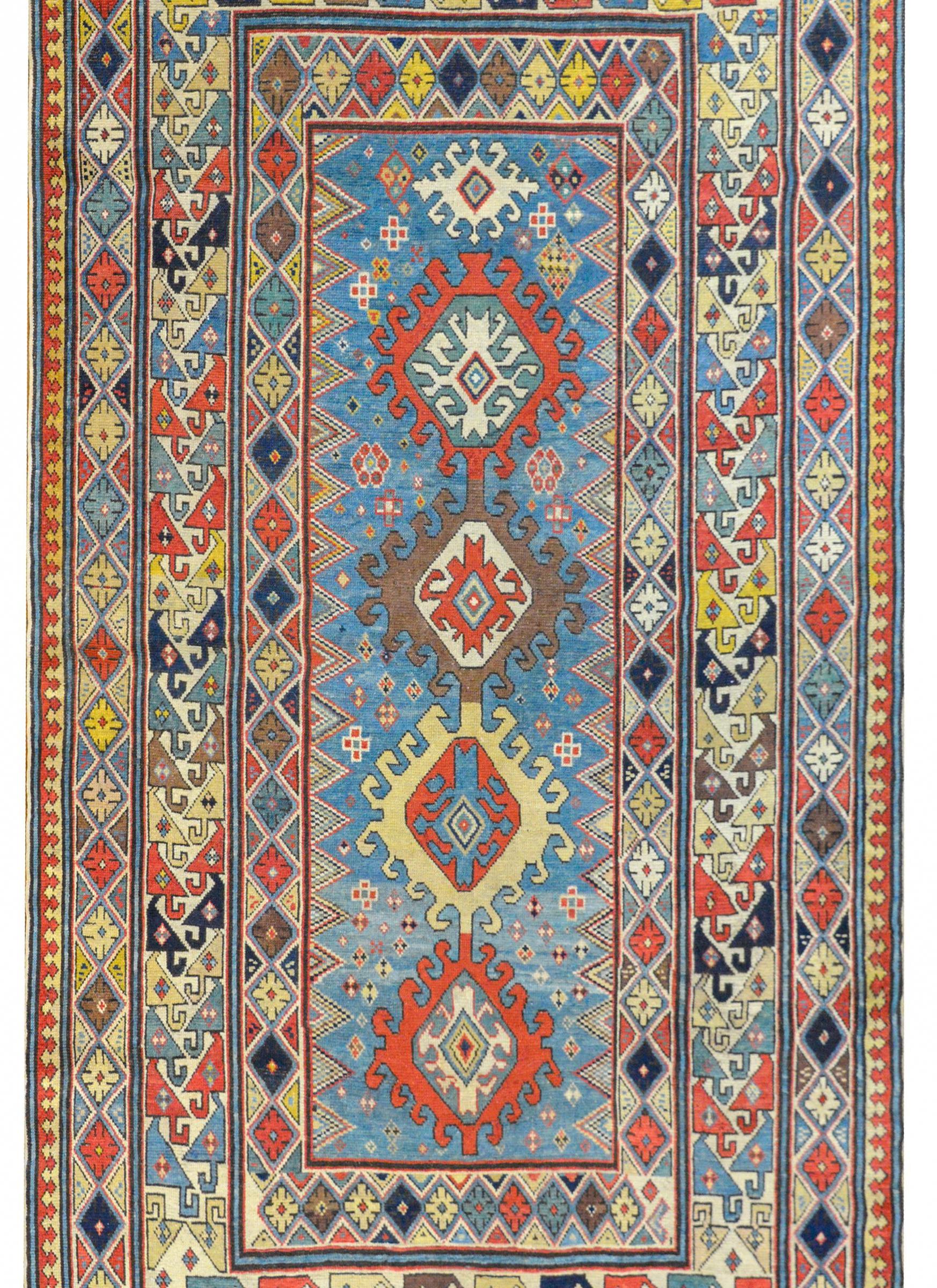 An incredible late 19th century Azerbaijani Kazak rug with several multicolored stylized floral medallions amidst a field of geometric patterned stylized flowers on a pale indigo field, surrounded by a wild border containing multiple multicolored