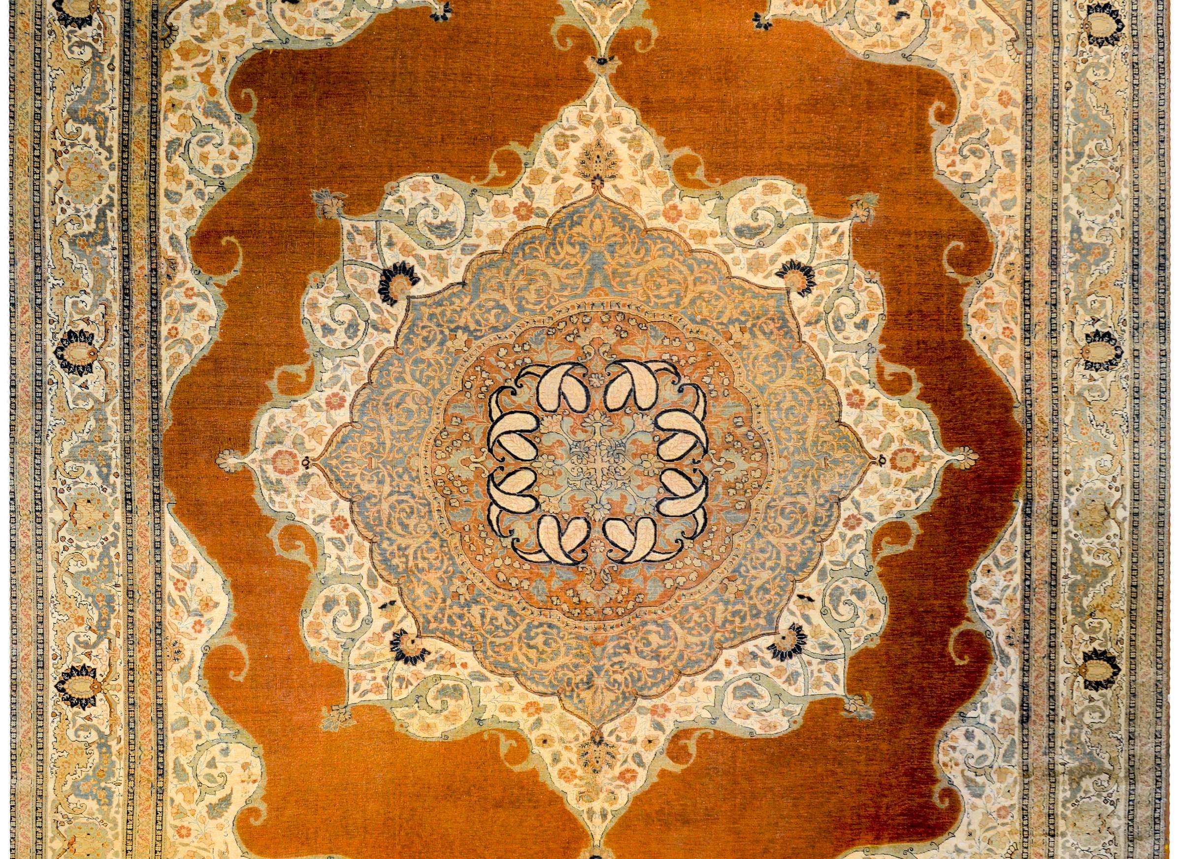 A wonderful late 19th century Persian Tabriz Haji Jalili rug with a mesmerizing pattern of intricately and tightly woven pattern of multicolored flowers on a bold orange background. The border is complex with a large central floral and leaf
