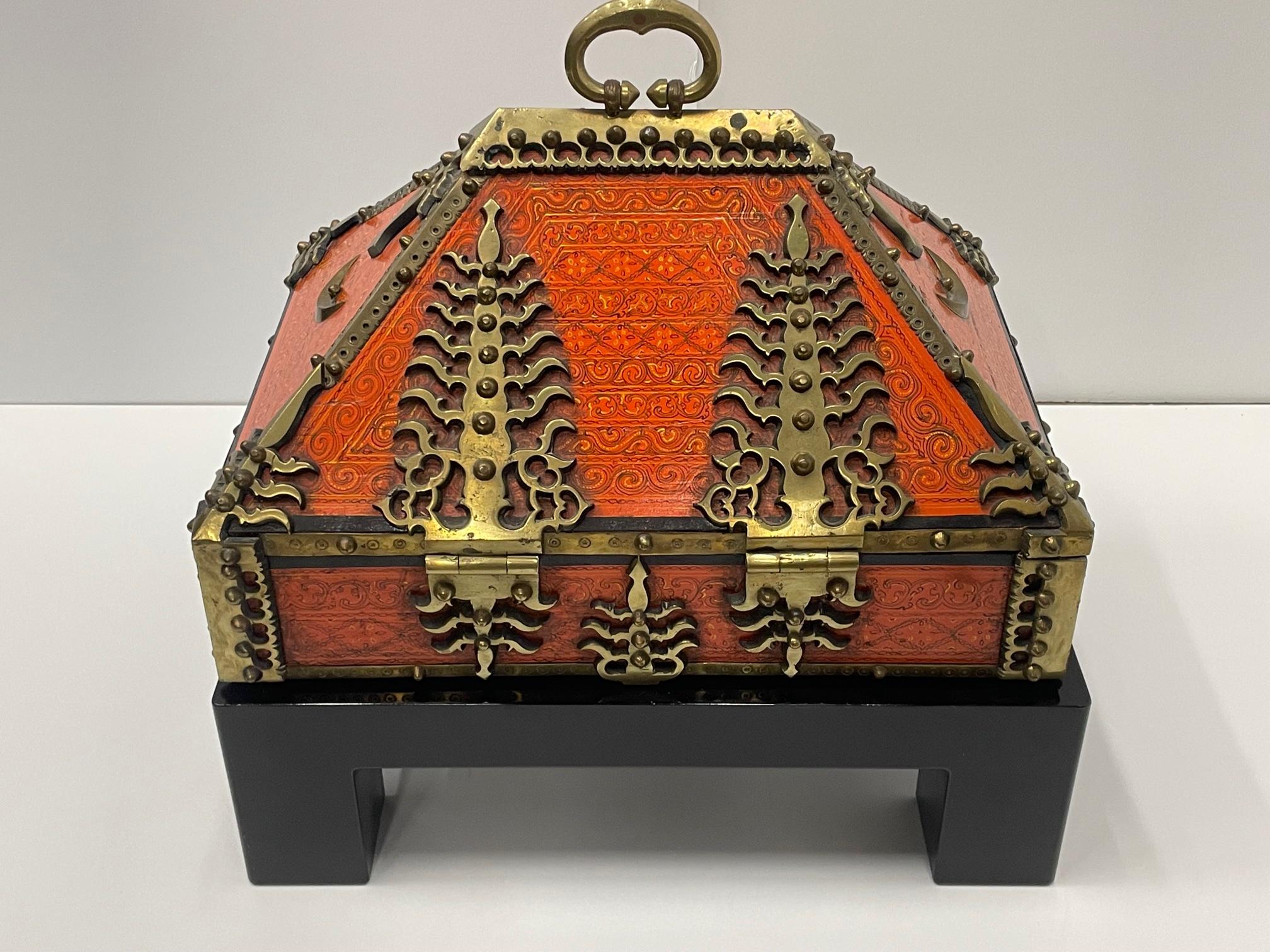 Extraordinary ornate red lacquered dowry box having unusual shape and amazing brass decoration and pen work. Original key included and an ebonized black custom stand.