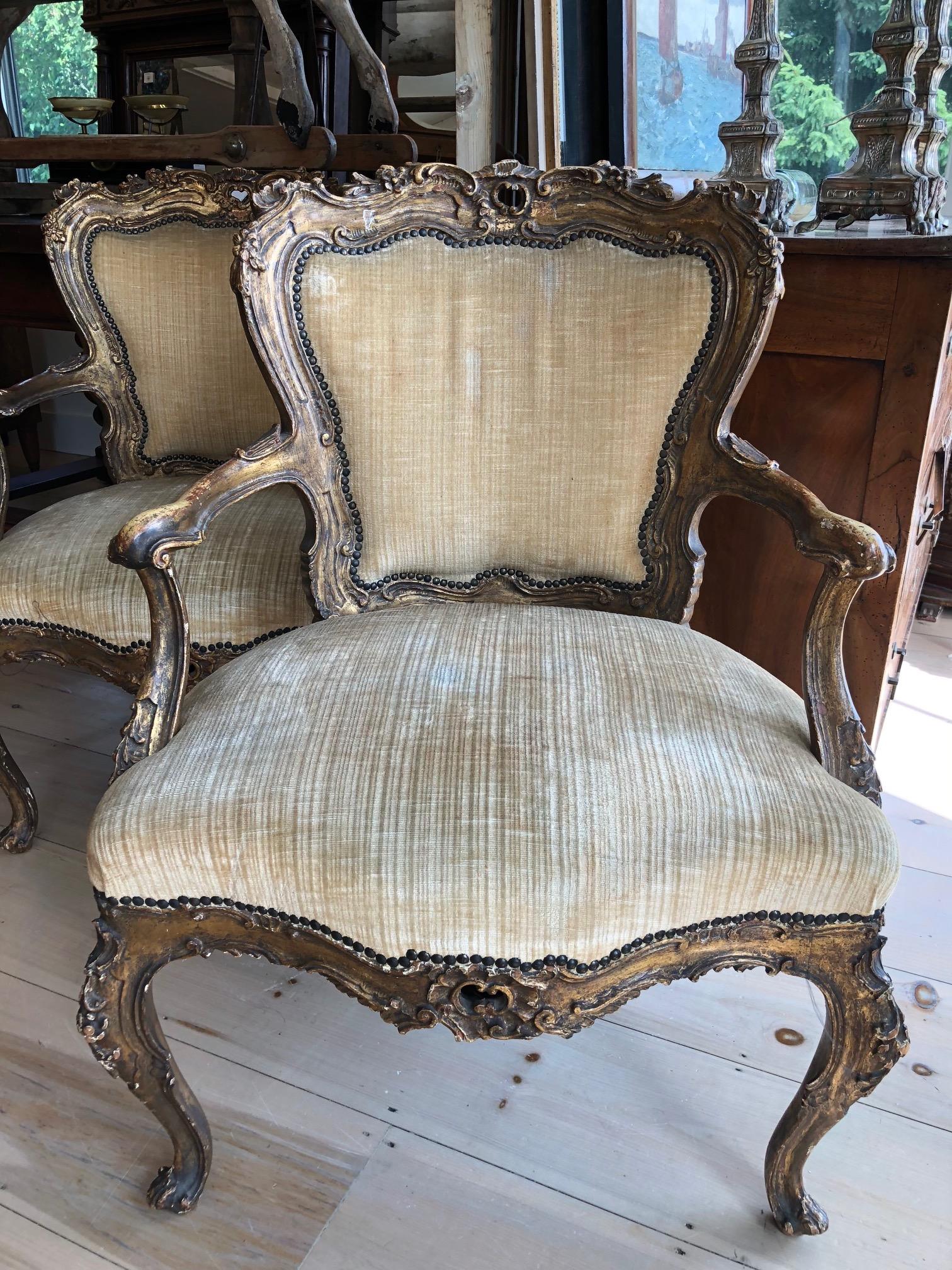 An original antique 19th century pair of museum quality lacquer and giltwood armchairs. These finely hand-carved comfortable armchairs have gorgeous sinuous lines typical of Louis XV period. Each fauteuil is masterfully handcarved, with twisted and