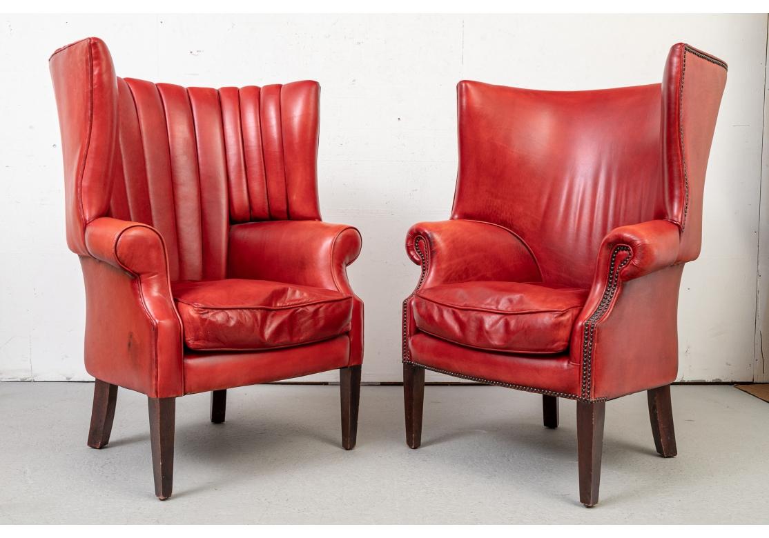 A Pair of very well made, solid feeling and comfortable Wing Chairs upholstered in a striking Lipstick Red Leather. Both of the Chairs have Traditional Flat-Panel Arms and Tapered Wood Legs while one of the Chairs has a Channel Back and the other