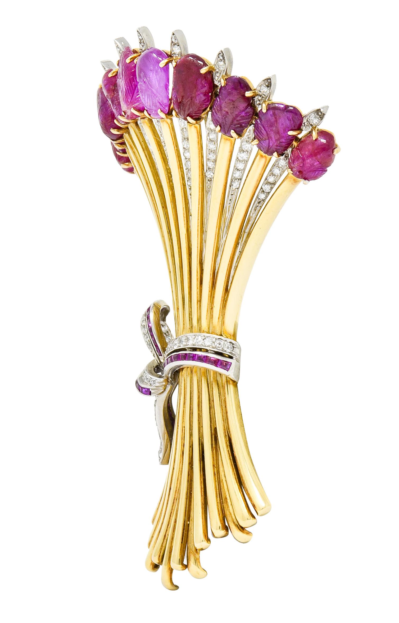 Brooch is designed as a bundle of wheat cinched by a platinum ribbon and flared polished gold stems

Terminating as a row of prong set rubies deeply carved with foliate motifs; red to purplish-red in color and translucent with natural