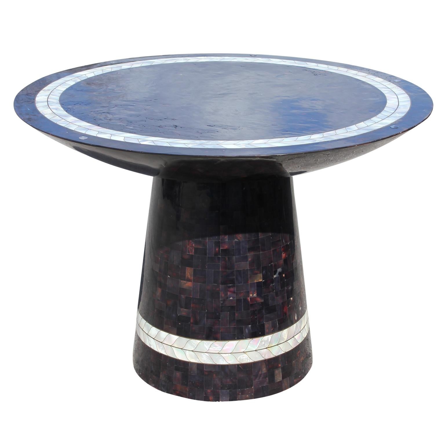 Attributed to Maitland Smith, this wonderful round pedestal dining table has a beautiful tessellated stone and pearl design. Superb quality and construction. It features a glass top that can be replaced with a larger size. Made in the the