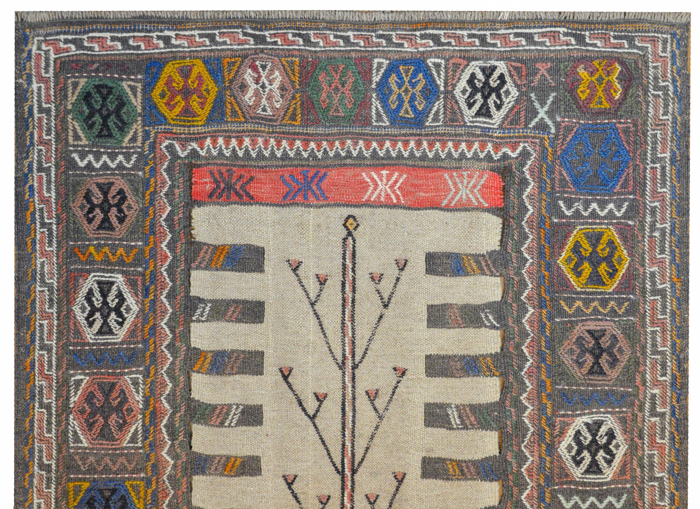 An incredible mid-20th century Afghani Baluch runner with a fantastic flat-weave pattern containing a stylized tree-of-life pattern down the center of the field, and a border with myriad stylized flowers.