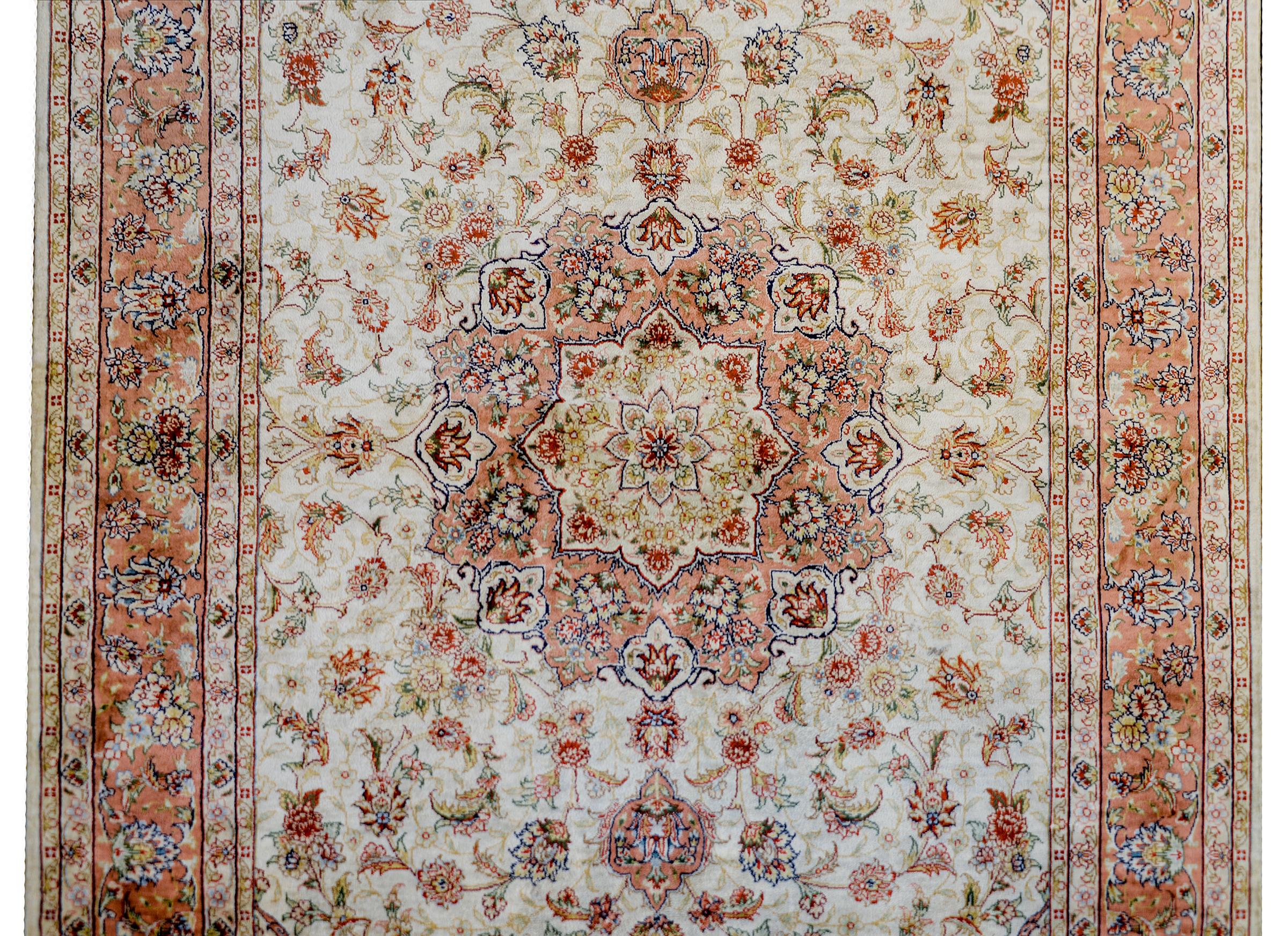 An incredible vintage Egyptian Tabriz patterned woven in100% silk with a beautiful central multi-lobed floral medallion woven in pink gold, indigo, crimson, and natural colored silk. The medallion lives amidst a field of myriad flowers with