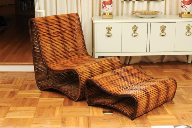 A rare pair of majestic large-scale slipper chairs and matching ottomans by the great Danny Ho Fong for Tropi-cal, circa 1970. Heavy wrought iron frame finished in bamboo, with handsome cane accents. Exceptional design, material selection and