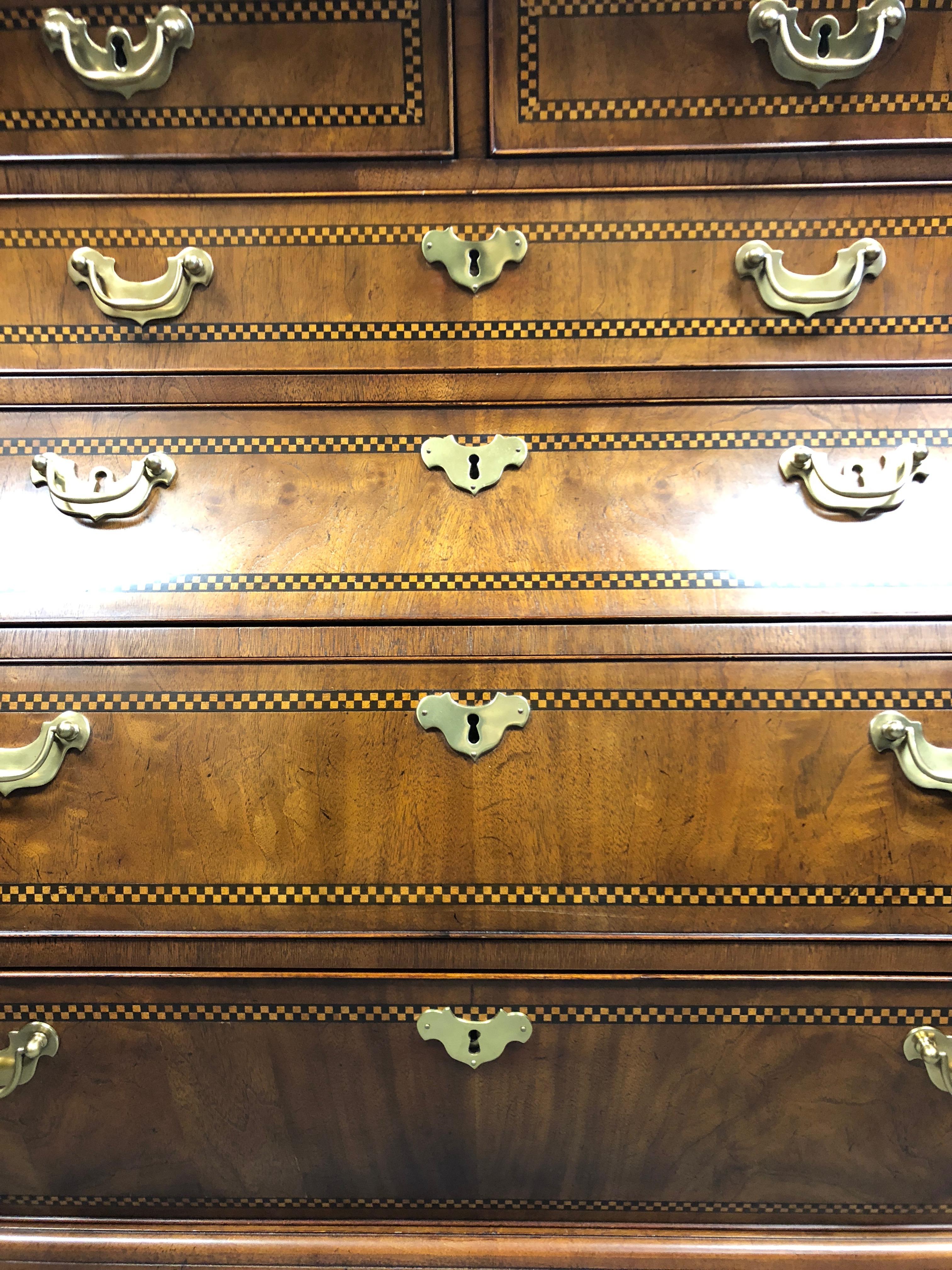 A top of the line beautifully made very large Bombay chest of drawers having an exaggerated curvy shape including angled well crafted drawers that function like silk. A mix of mahogany with ebony and satinwood inlaid checkerboard decoration, brass