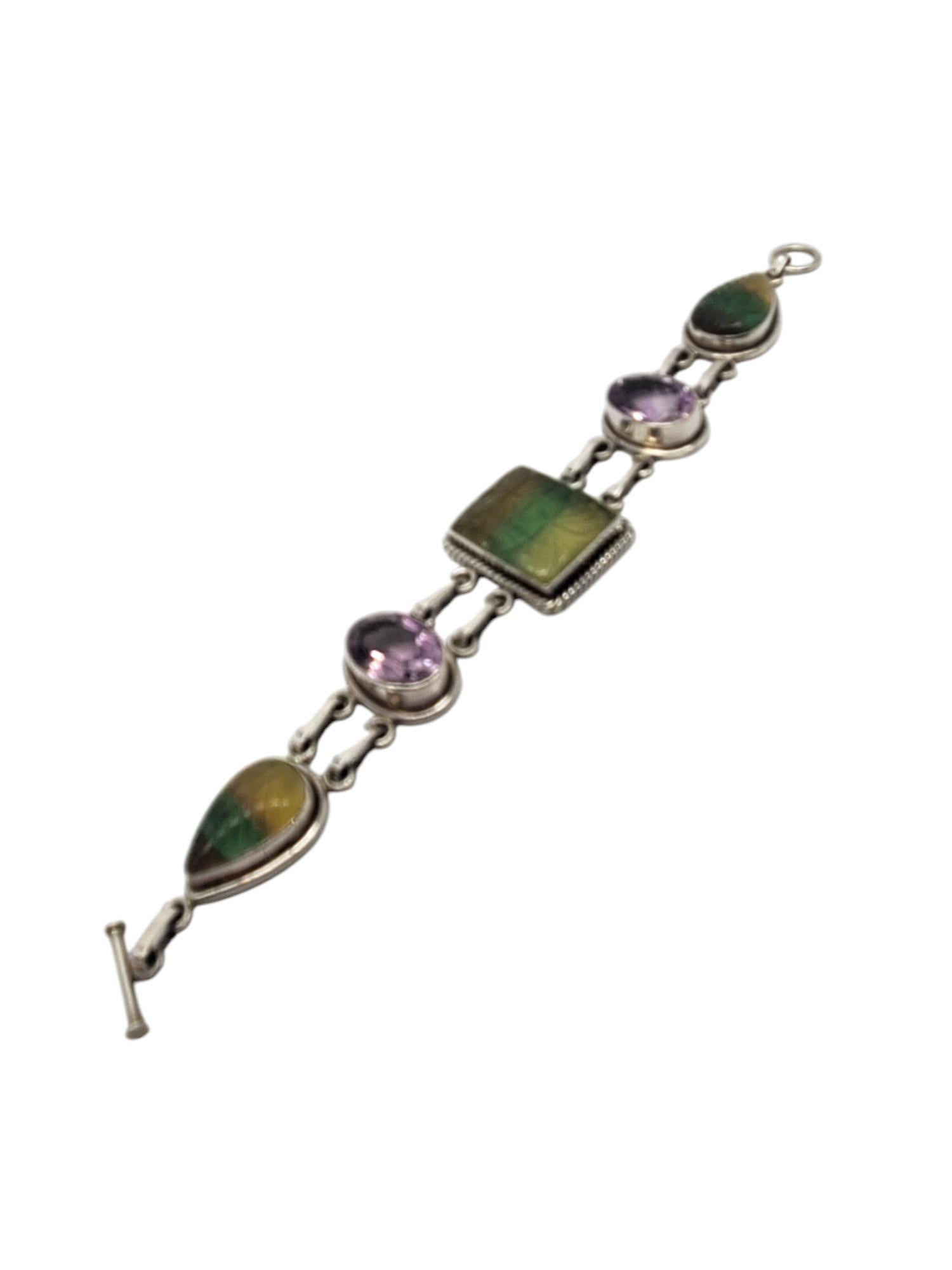 India 925 Bracciale A Link con più pietre preziose intagliate

Questo braccialetto unico con alamari presenta 3 gemme intagliate con un motivo a forma di foglia e 2 gemme ovali sfaccettate di colore viola collegate con maglie incastonate