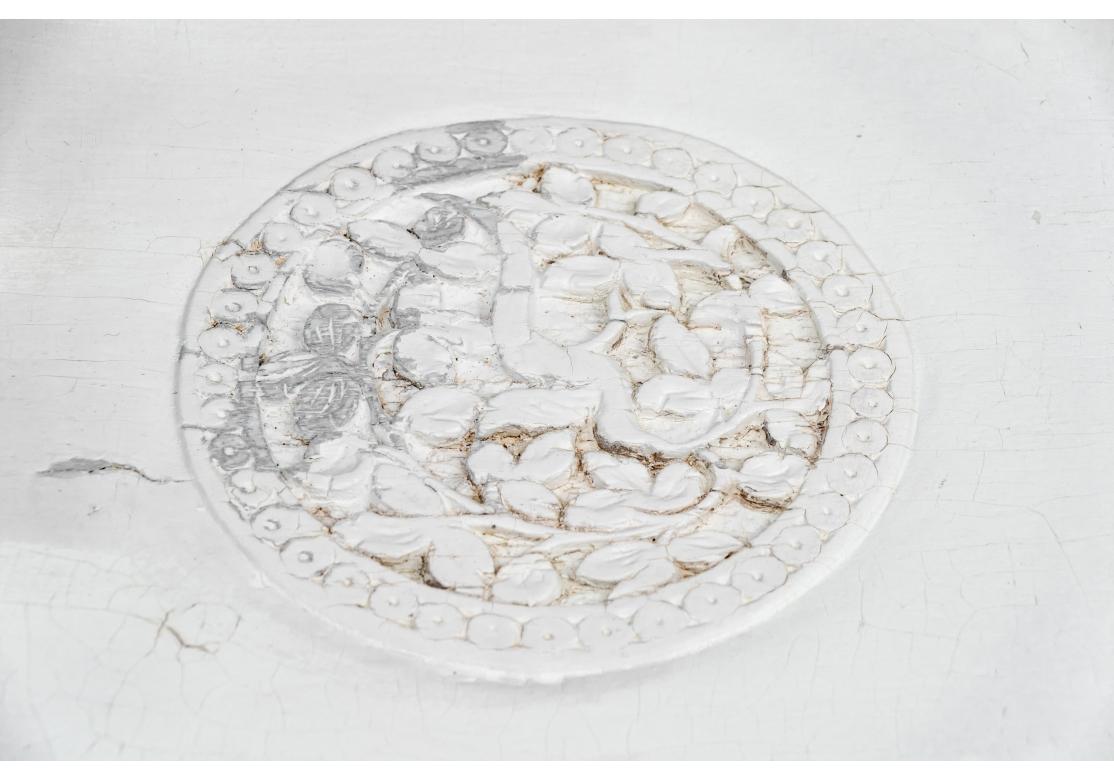An ornately hand-carved round pedestal table with a carved top with foliate panels alternating with leafy ones and with a center foliate medallion. A wide pierced, scalloped openwork foliate apron surrounding the top. With a figural tripod support