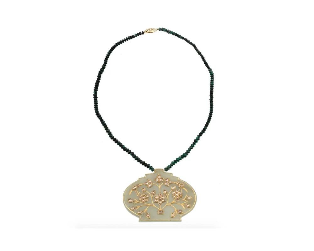 An Indian Mughal 14K Yellow Gold necklace with a pendant. The necklace is made of 11.64 cts Emerald stones in a beaded design. The pendant is made of hand carved Jade with scalloped rims, decorated with a floral ornament, and encrusted with