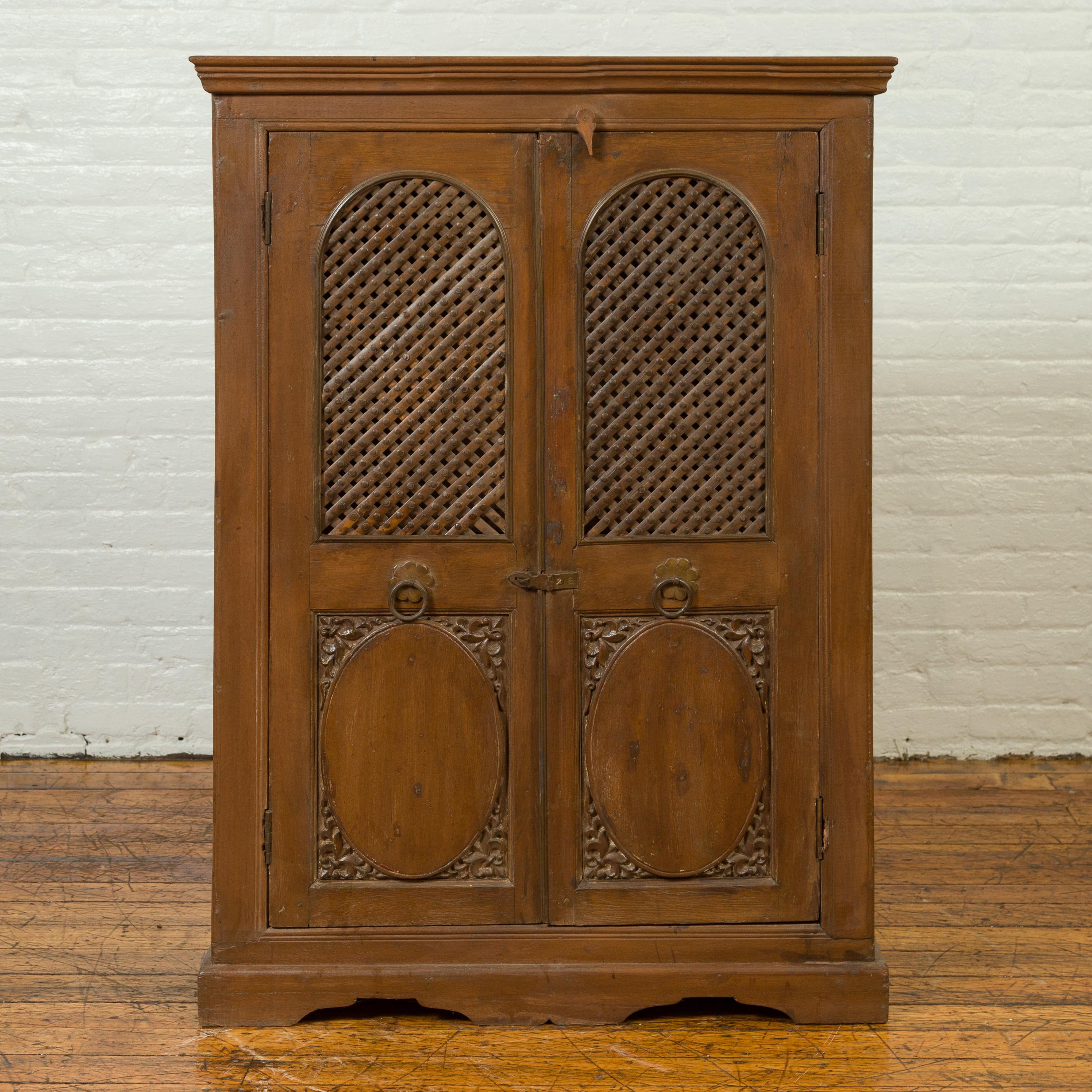An Indian wooden kitchen cabinet from the 19th century, with metal fretwork motifs and oval medallions. Crafted in India during the 19th century, this kitchen cabinet features a molded cornice sitting above two large doors, adorned with metal