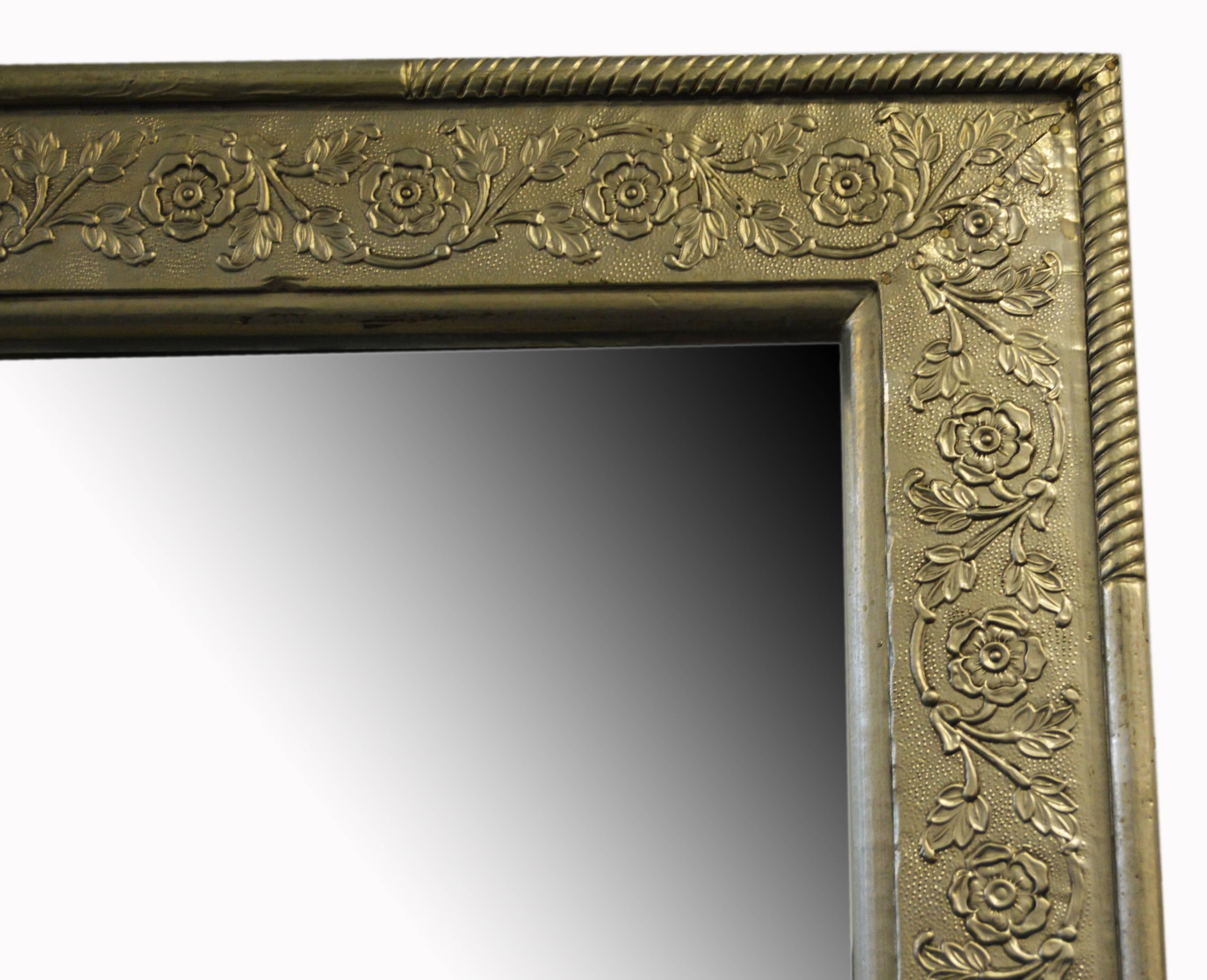 An antique 19th century Indian silver-plated rectangular mirror, hand-hammered brass over wood. This Indian silver-plated mirror features a rectangular frame, adorned with an exquisite décor of arabesques of flowers, whose sinuous arrangement gently