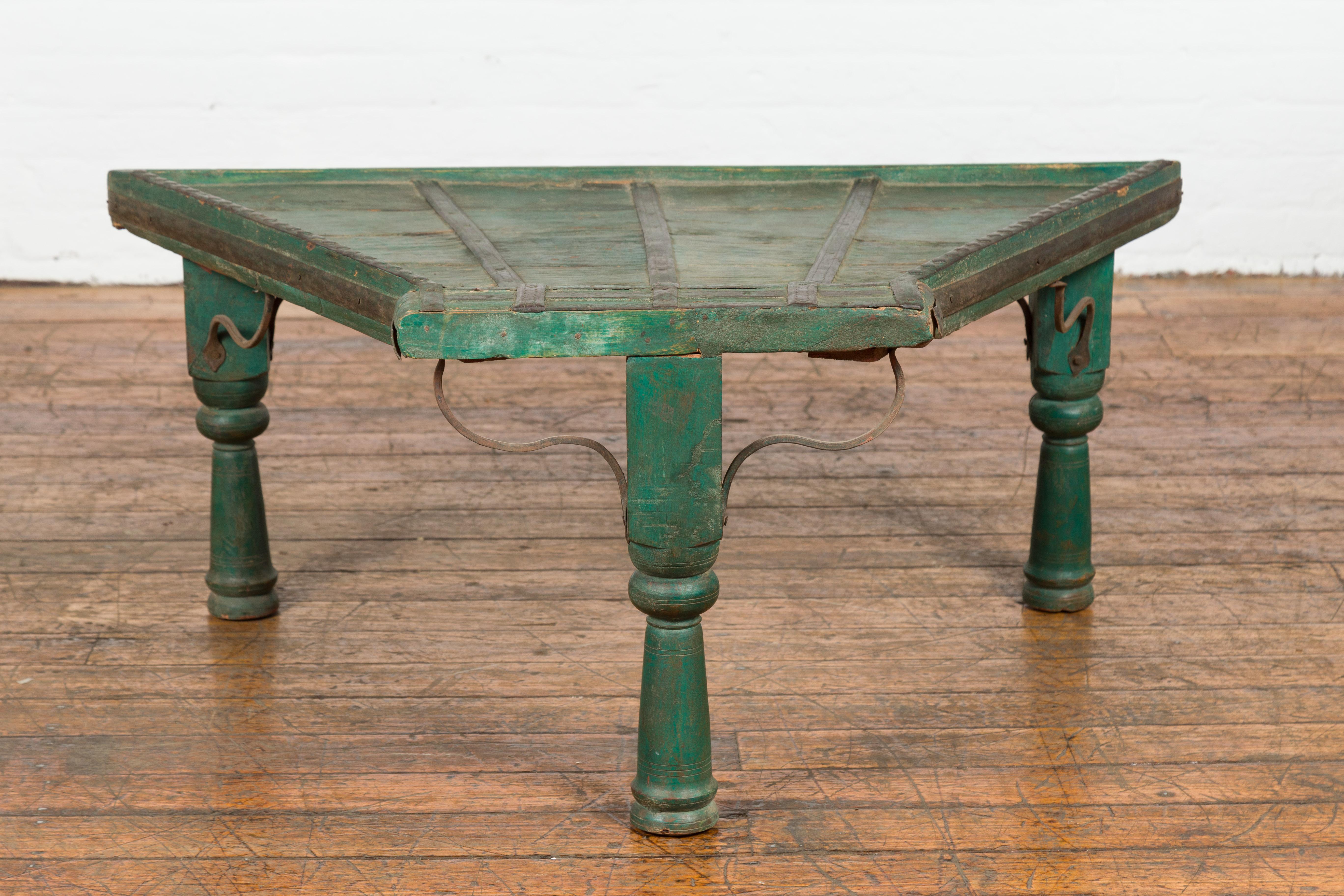 Rustic Indian green painted coffee table crafted from a repurposed bullock cart from the 19th century with curved iron stretchers, nicely weathered patina, turned baluster Legs, iron braces, diamond motifs on the top's edges and wavy patterns in the