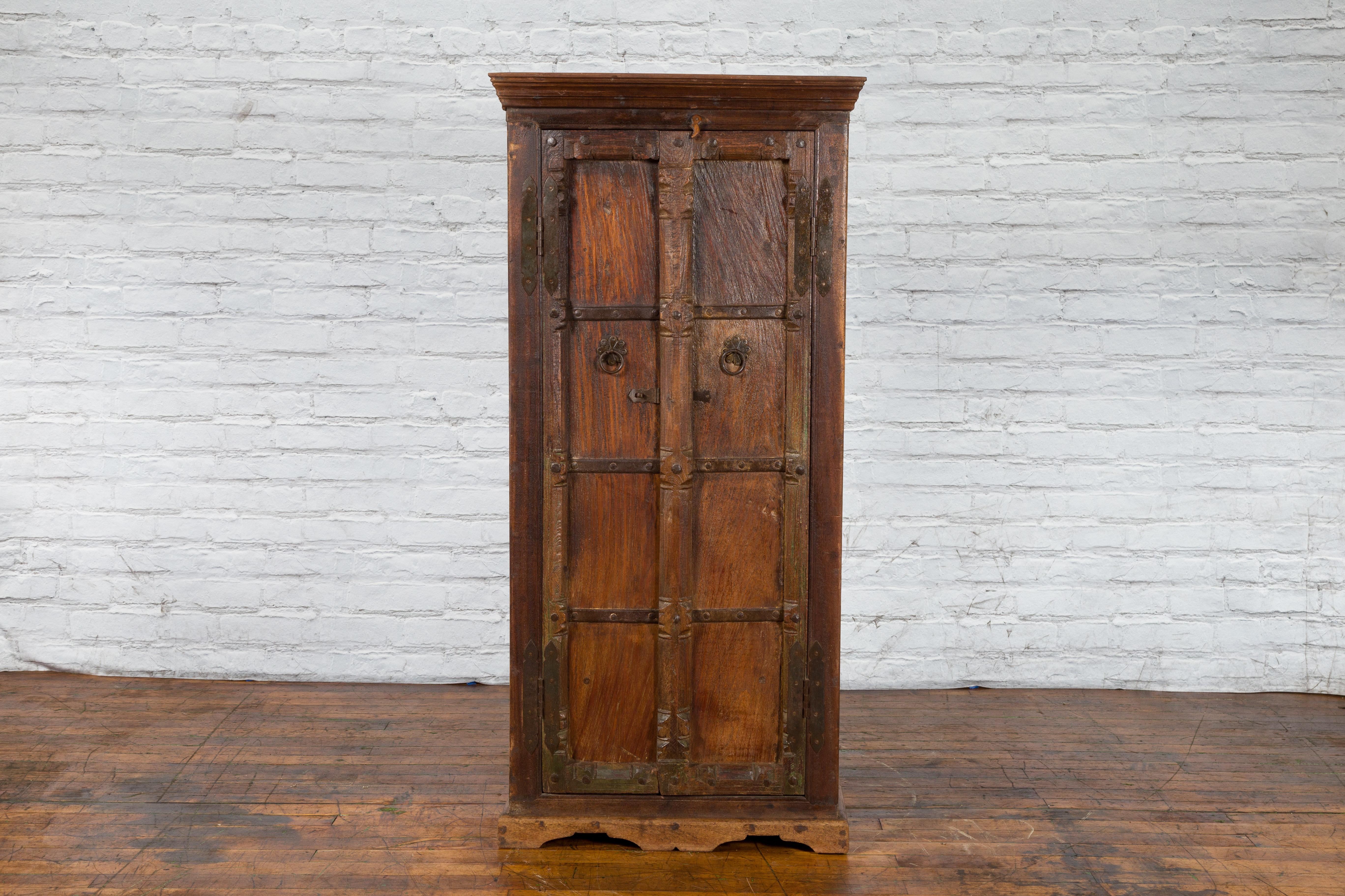 An Indian Gujarat rustic hand-carved wooden armoire from the 19th century, with iron braces and half-columns. Created in Western India during the 19th century, this handsome Gujarat wooden armoire features a molded and beveled cornice gently leading