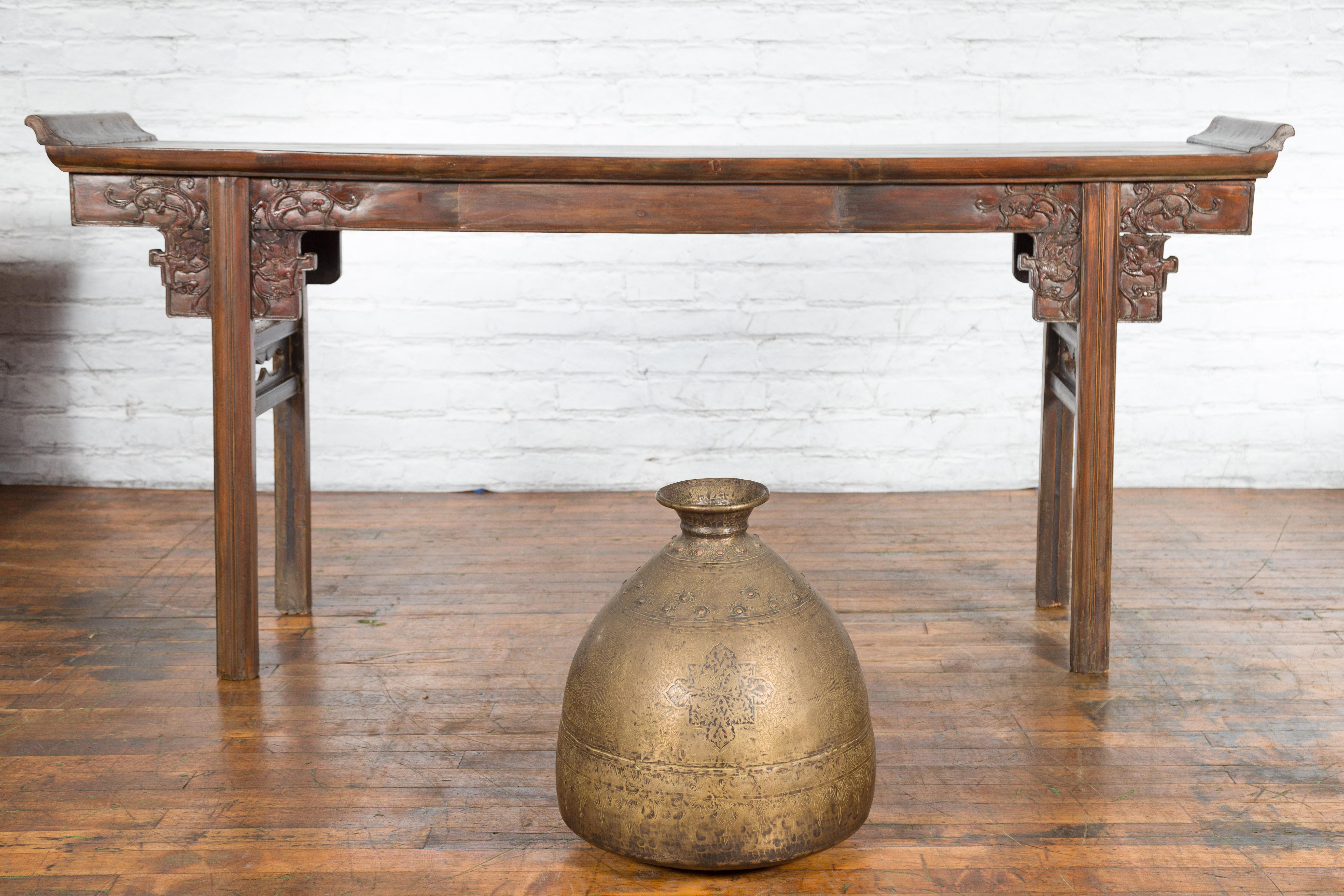 An Indian brass vase from the 19th century, with etched floral décor. Created in India during the 19th century, this large brass vase captures our attention with its generous lines and skillfully etched foliage décor. Showcasing a small opening