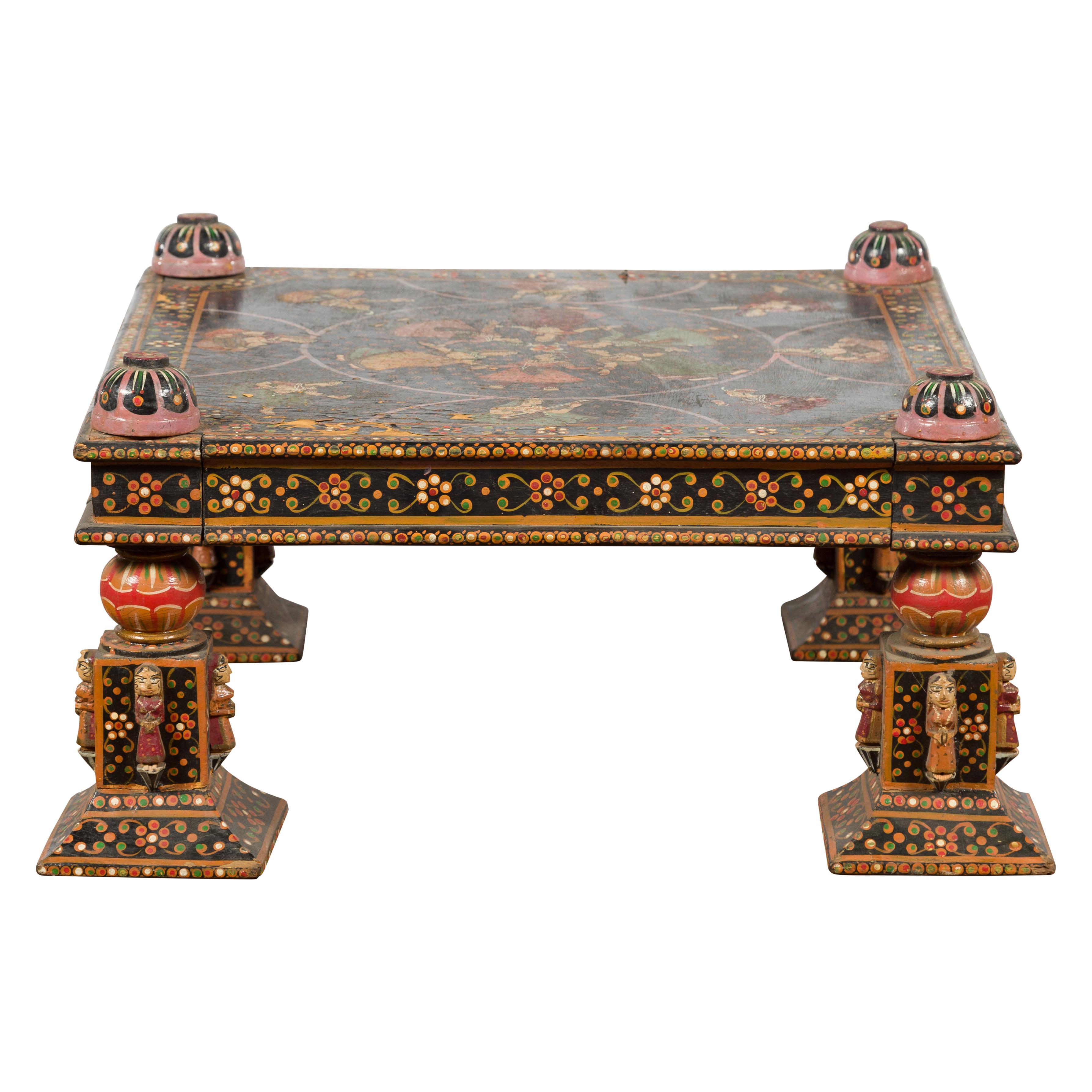 An Indian low coffee table from the 19th century, with hand-painted floral motifs and dancers. Created in India during the 19th century, this low coffee table features a square top adorned with dancers and musicians, sitting above a floral-themed