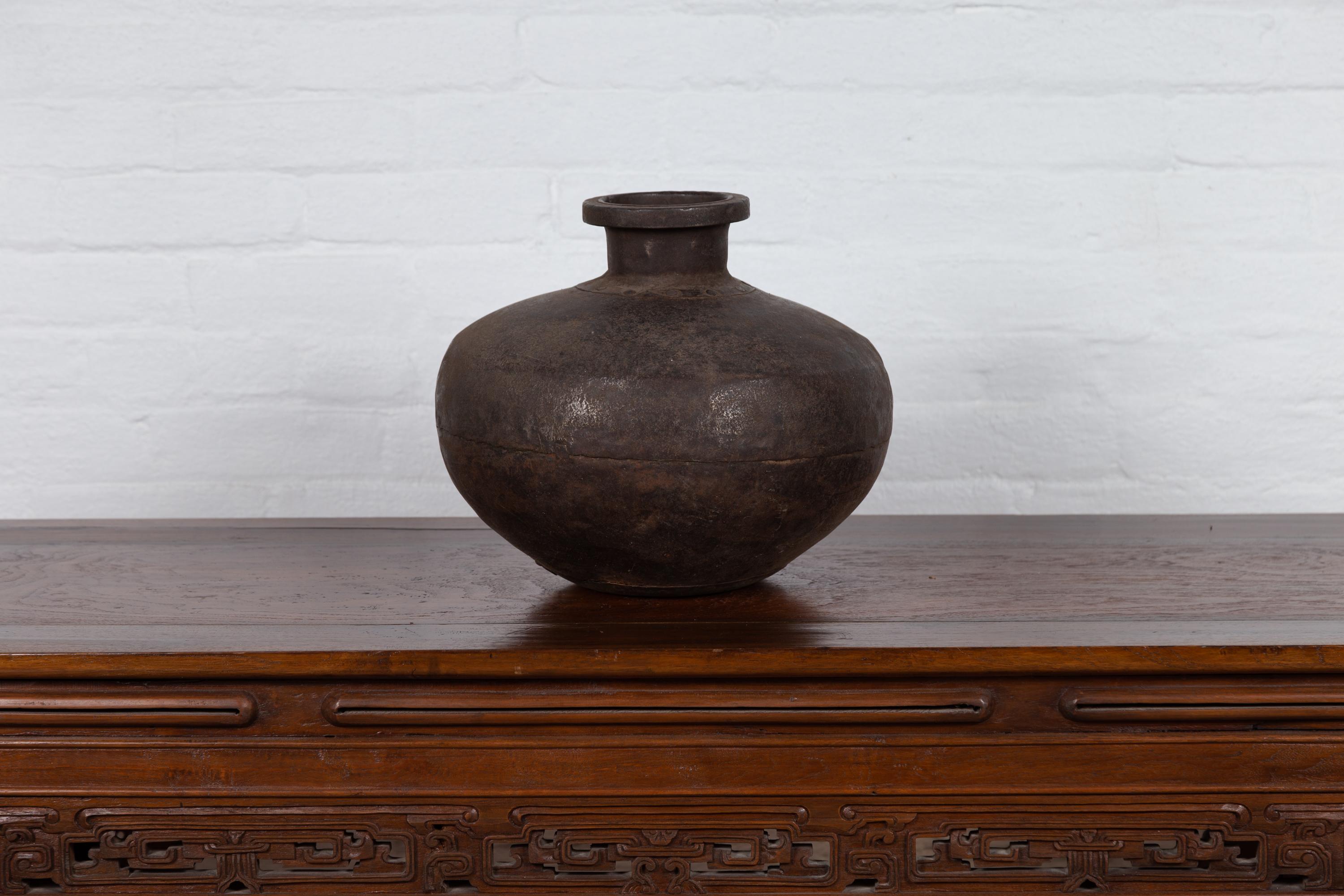 An antique Indian metal water jar from the 19th century, with large belly, slender neck and large lip. Born in India during the 19th century, this metal water jar charms our eyes with its generous Silhouette and nicely weathered patina. Presenting a