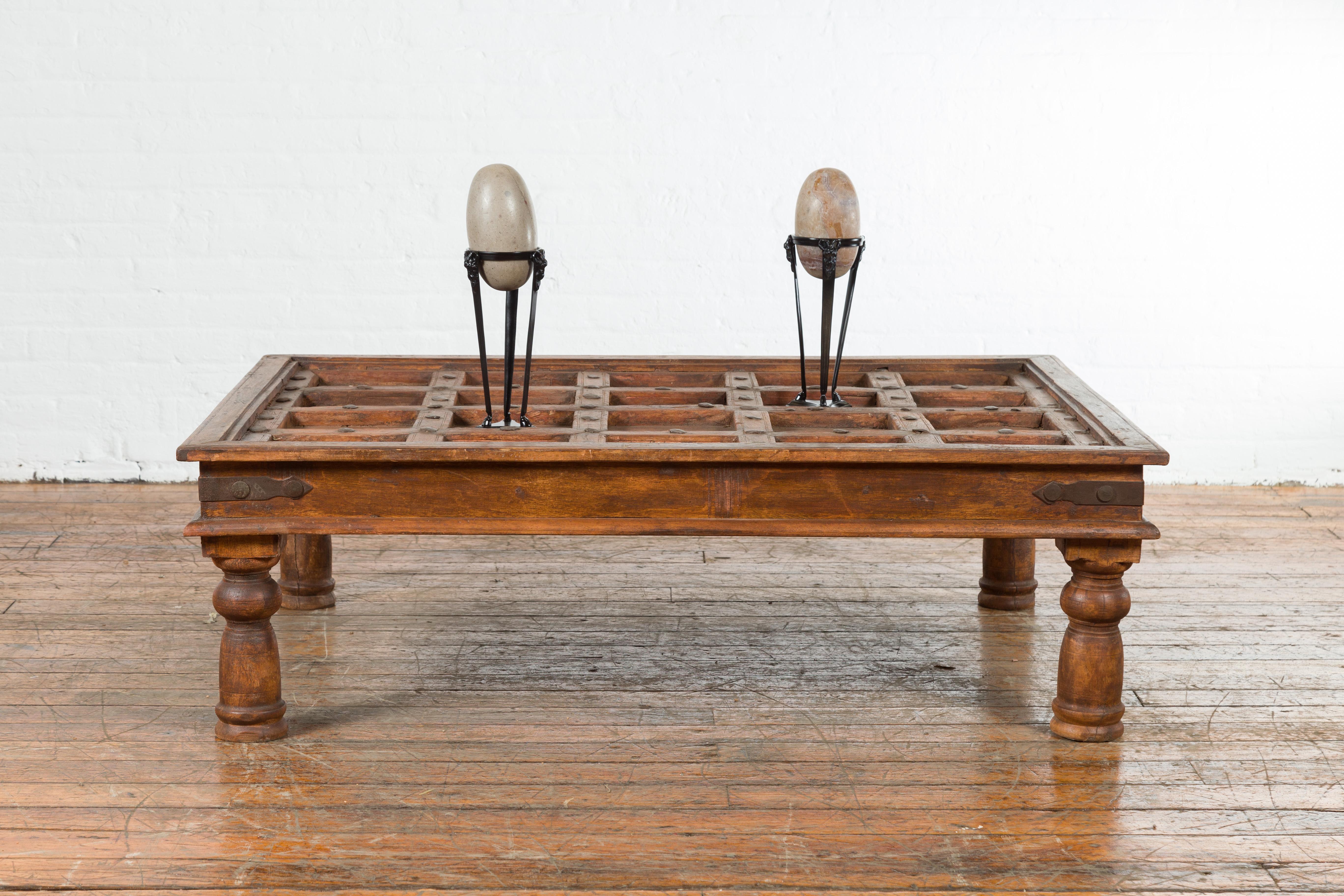 An Indian antique door with iron accents from the 19th century, turned into a coffee table. Created in India during the 19th century, this antique door has been made into a coffee table. The top, showcasing a succession of recessed panels, is