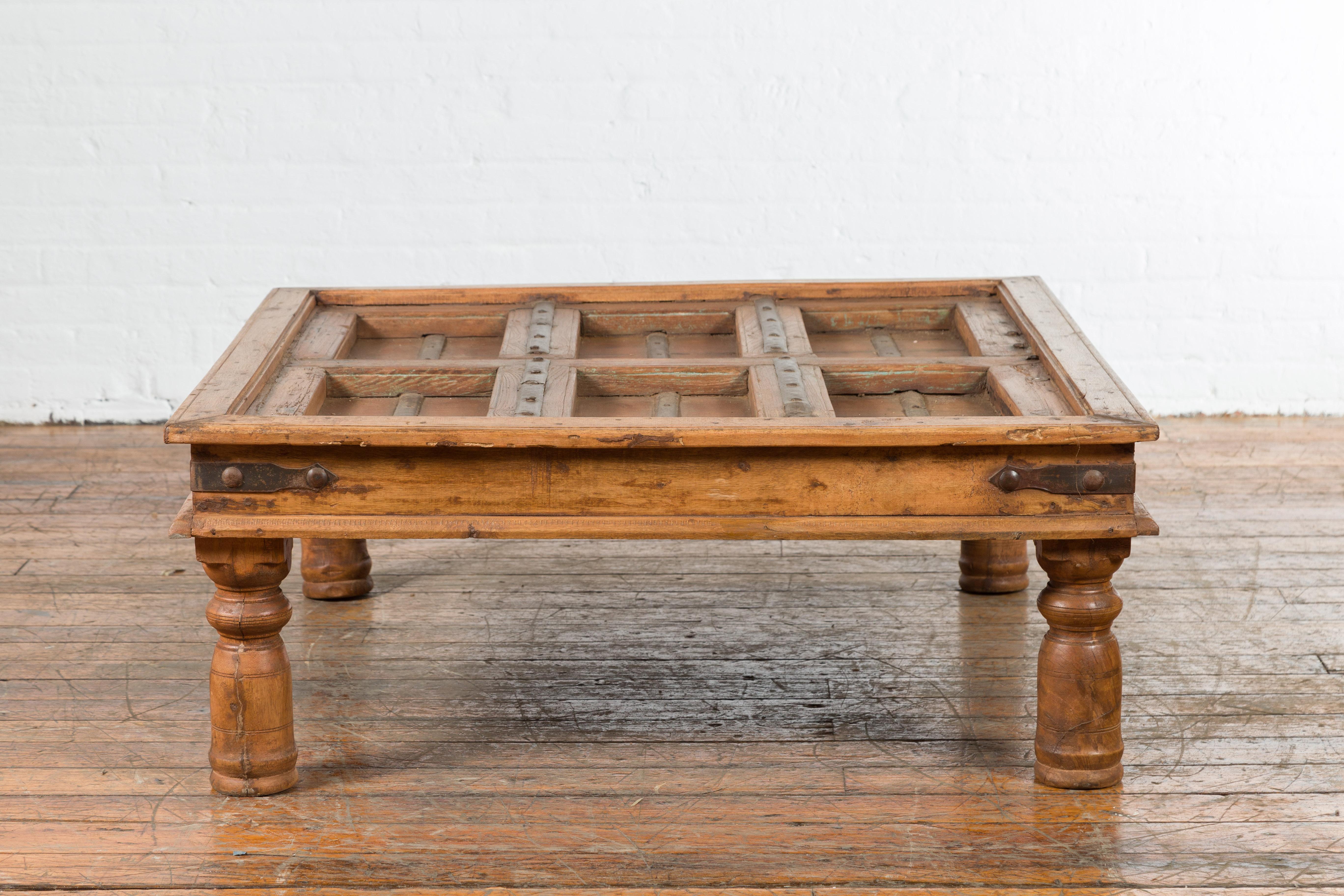 An old 19th century door from India that has been expertly converted into an antique coffee table. The antique door showcases a succession of recessed panels and is accented with iron studs. Our unique antique table is beveled so that you can fit a