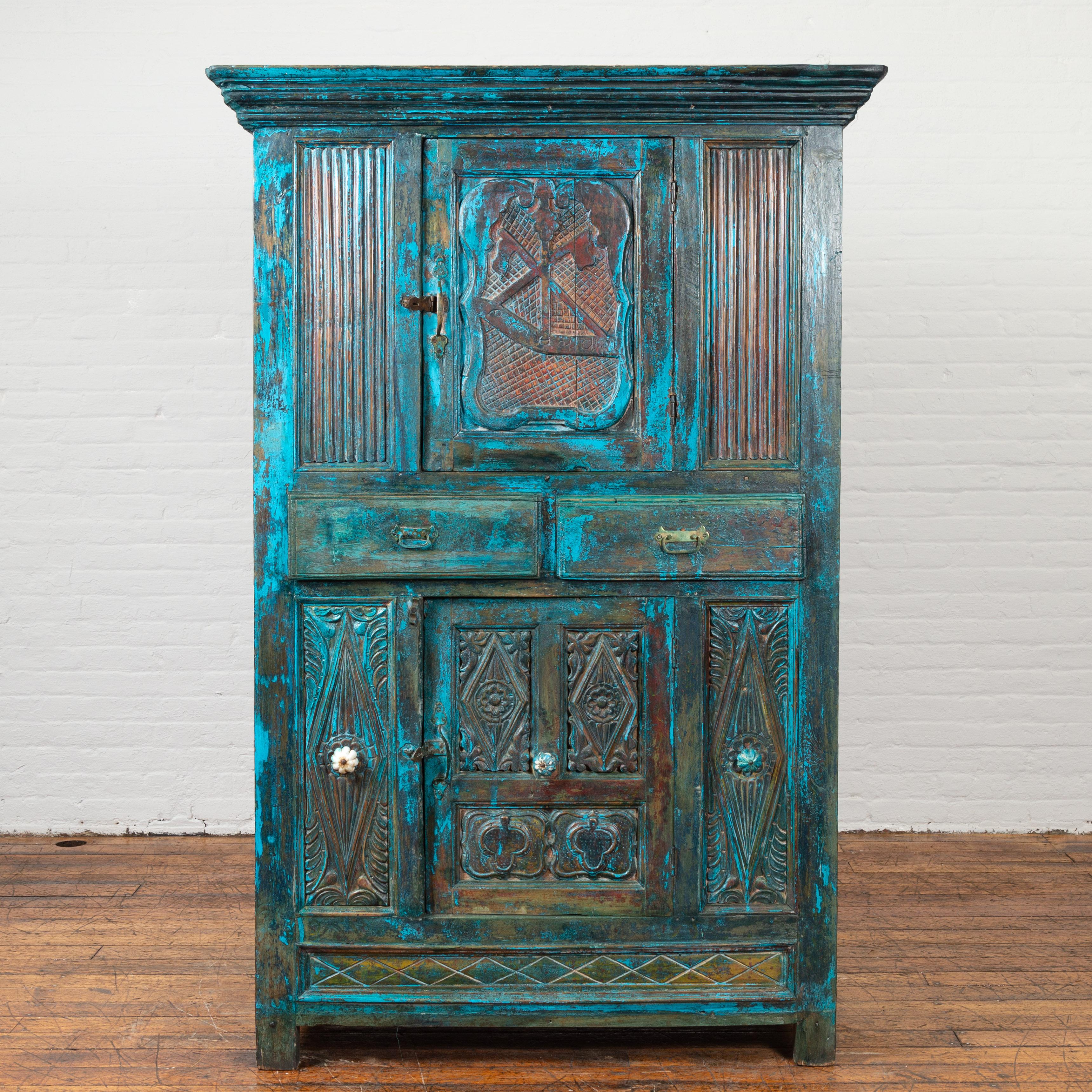 An Indian antique painted cabinet from the 19th century, with royal teal patina, carved doors and drawers. Created in India during the 19th century, this unusual cabinet features a molded cornice sitting above a single cartouche-carved door, flanked