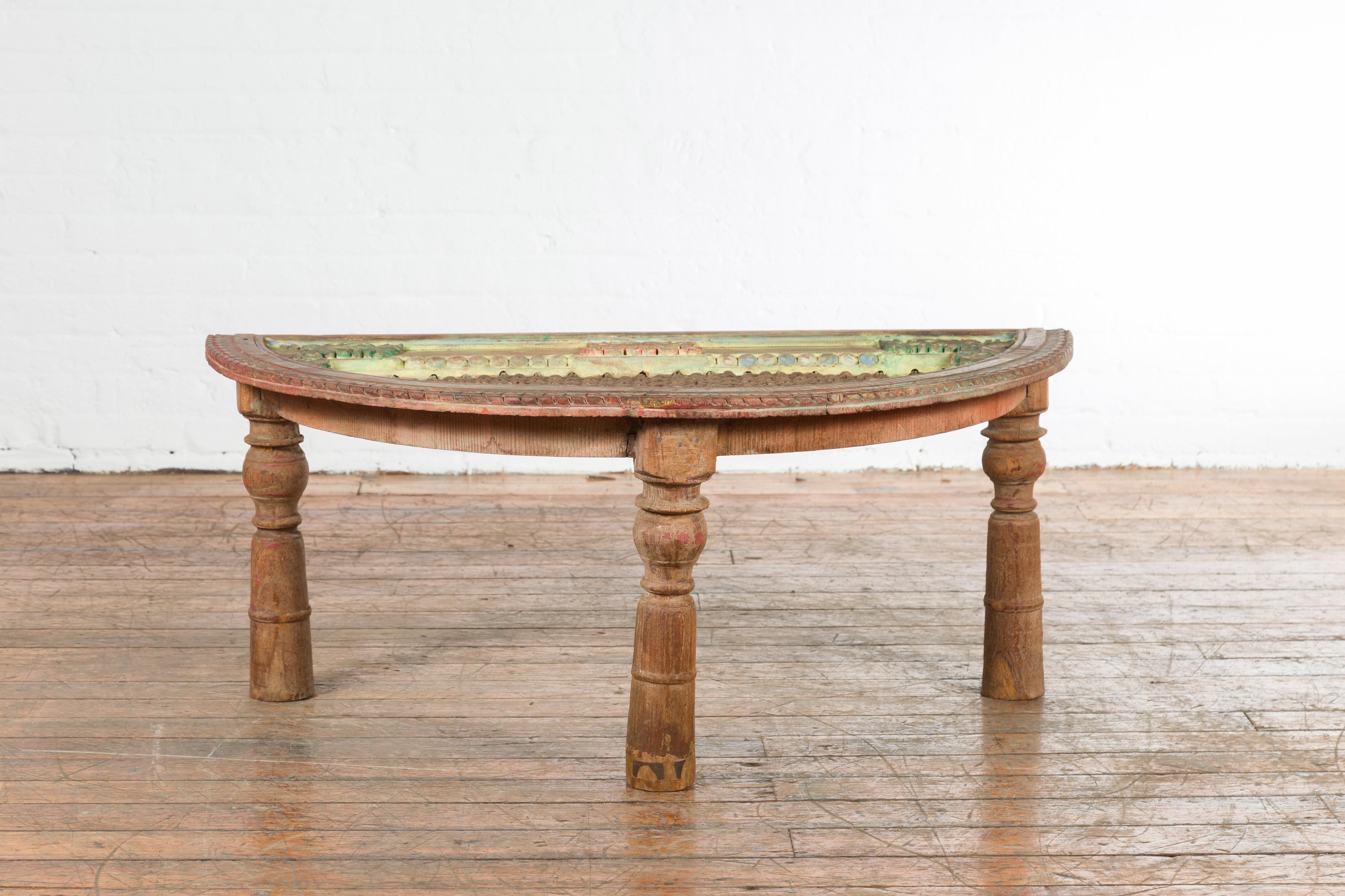 An Indian antique sheesham wood low demilune table from the 19th century, with window grate iron top, pastel accents and turned baluster legs. Created in India during the 19th century, this sheesham wood demi-lune features a semi-circular top