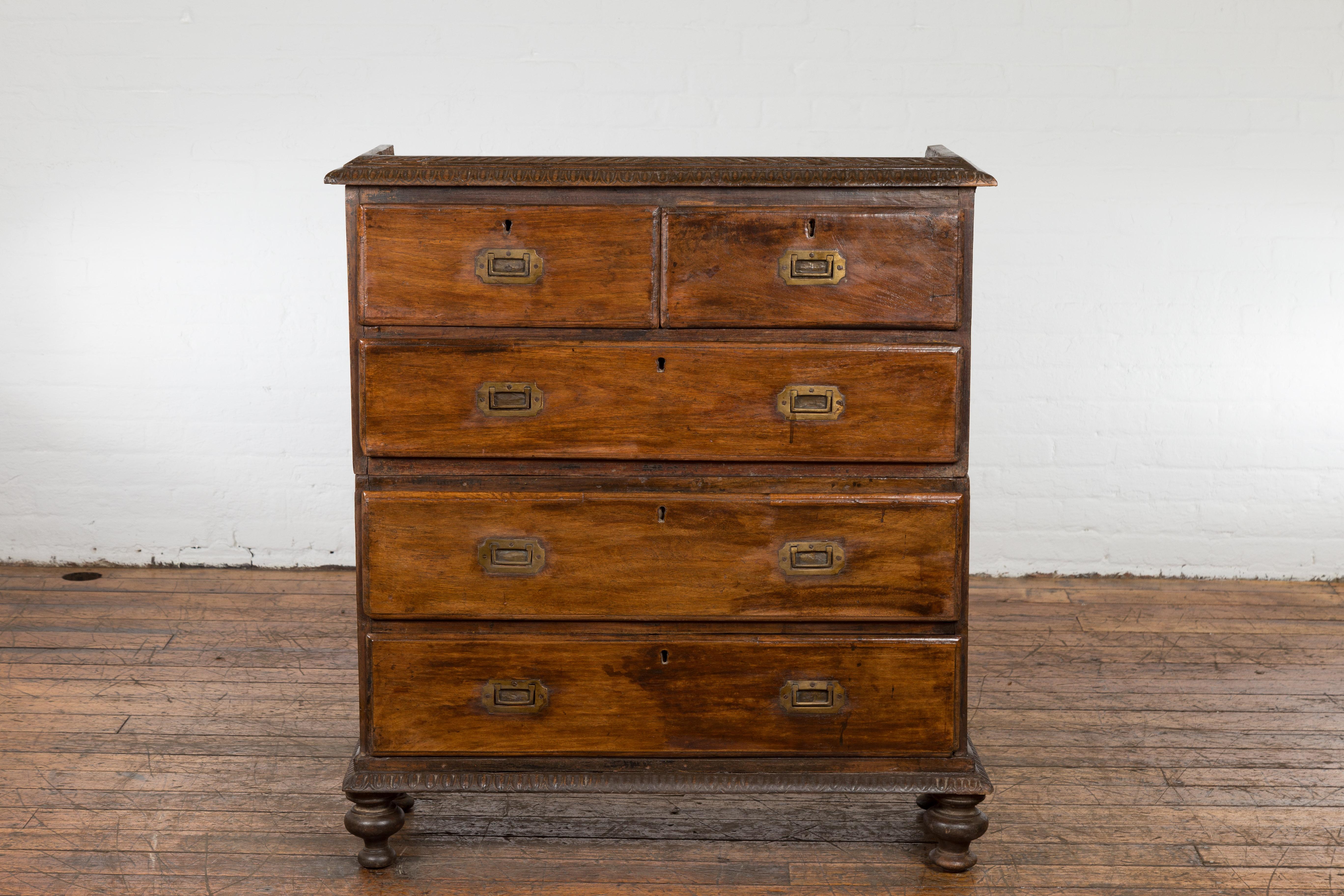An antique Indian two-part chest from the 19th century with five drawers, linear brass hardware and turned feet. Emanate a sense of simple elegance in your interior space with this 19th-century Indian two-part chest. Crafted with exactitude and