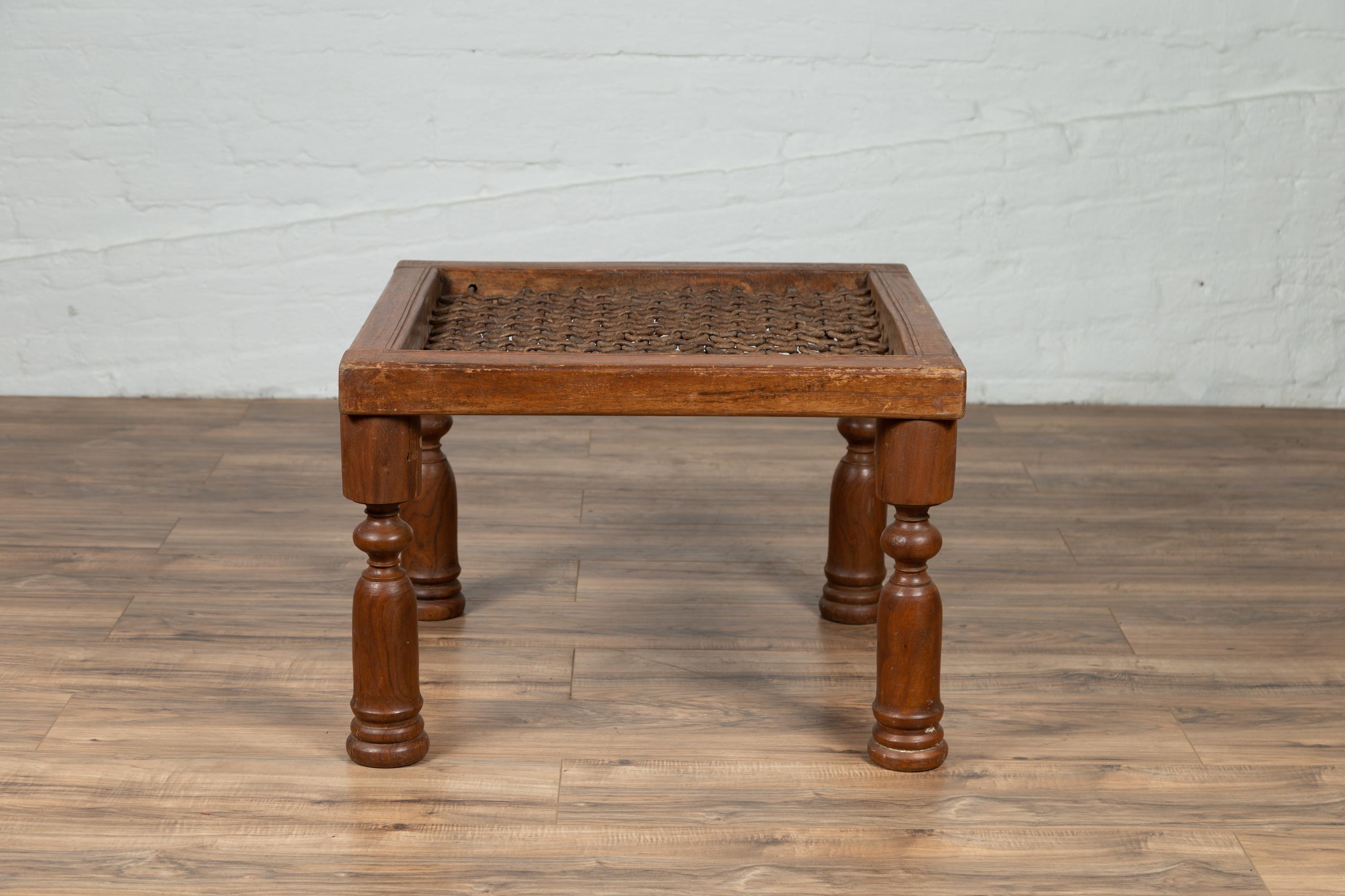 An Indian window gate from the 19th century made into a side table with turned baluster legs. Born in India during the 19th century, this square-shaped window gate adorned with metal accents, is sitting above four turned baluster legs, whose rounded