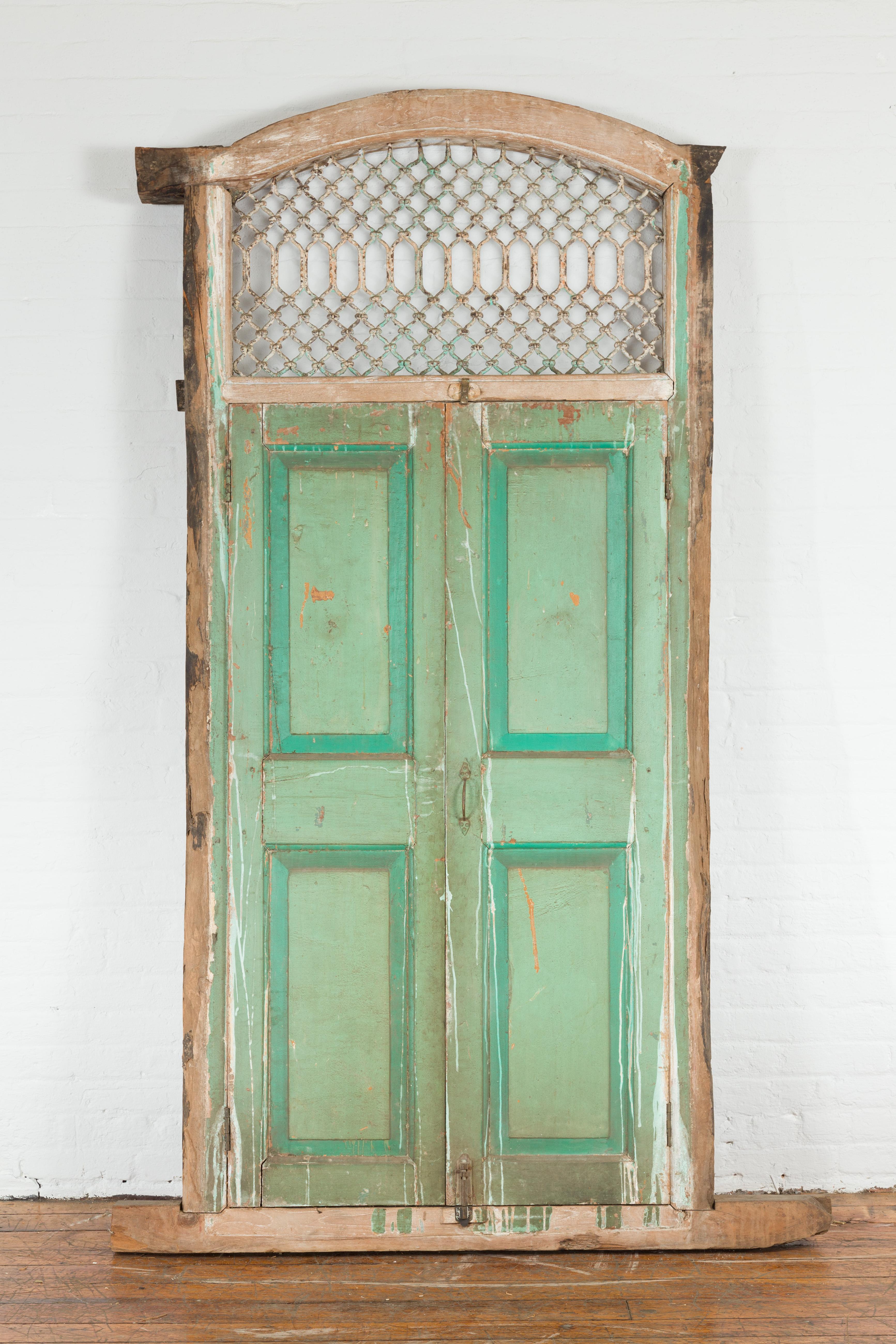 An Indian antique solid wood and iron grate window from the early 20th century, with green paint and distressed patina. Created in India during the early years of the 20th century, this antique tall window features a nicely distressed wooden