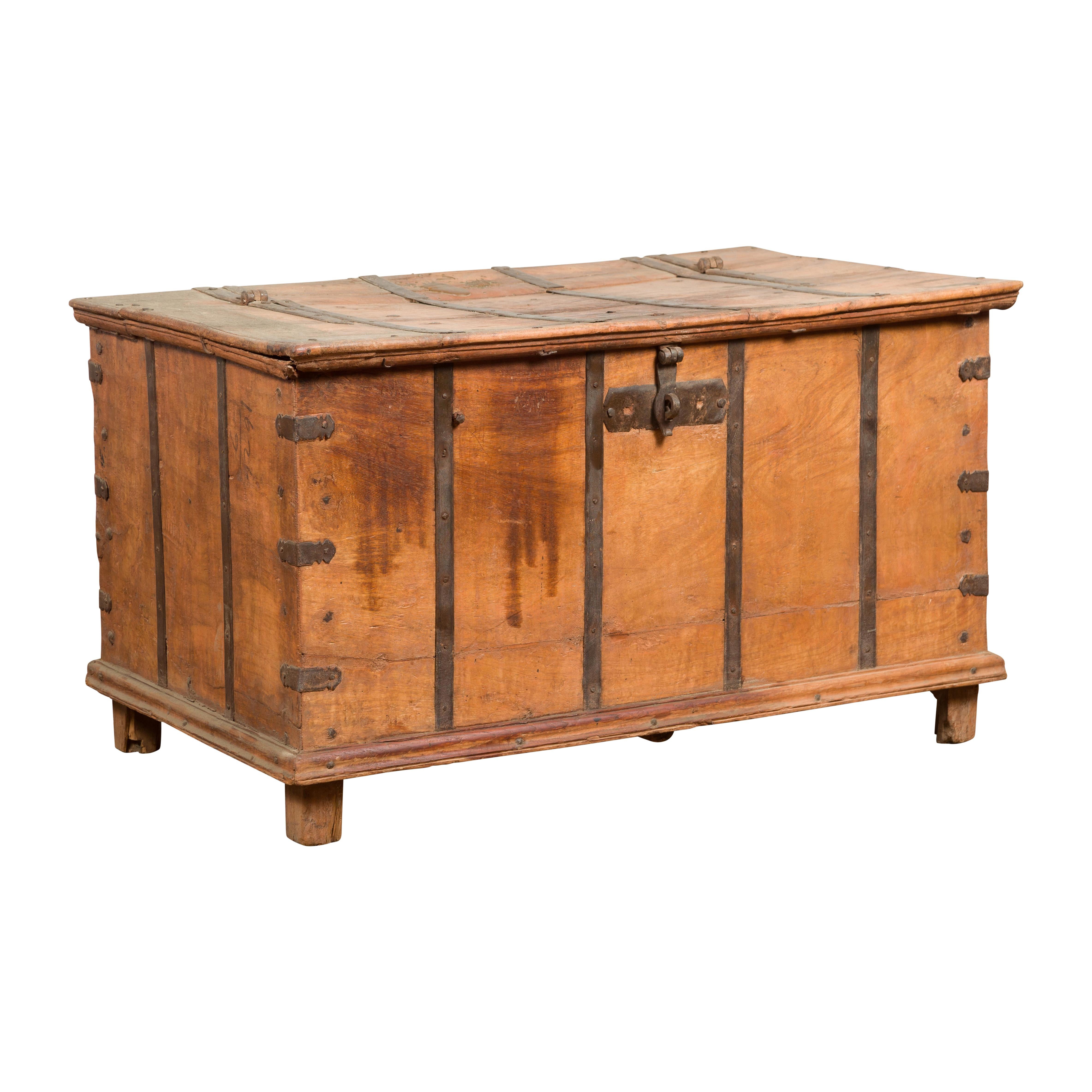 An antique Indian blanket chest from the 19th century with iron braces and hidden storage compartment. Embrace the rustic allure of this antique Indian blanket chest from the 19th century. With its weathered appearance and charming character, this