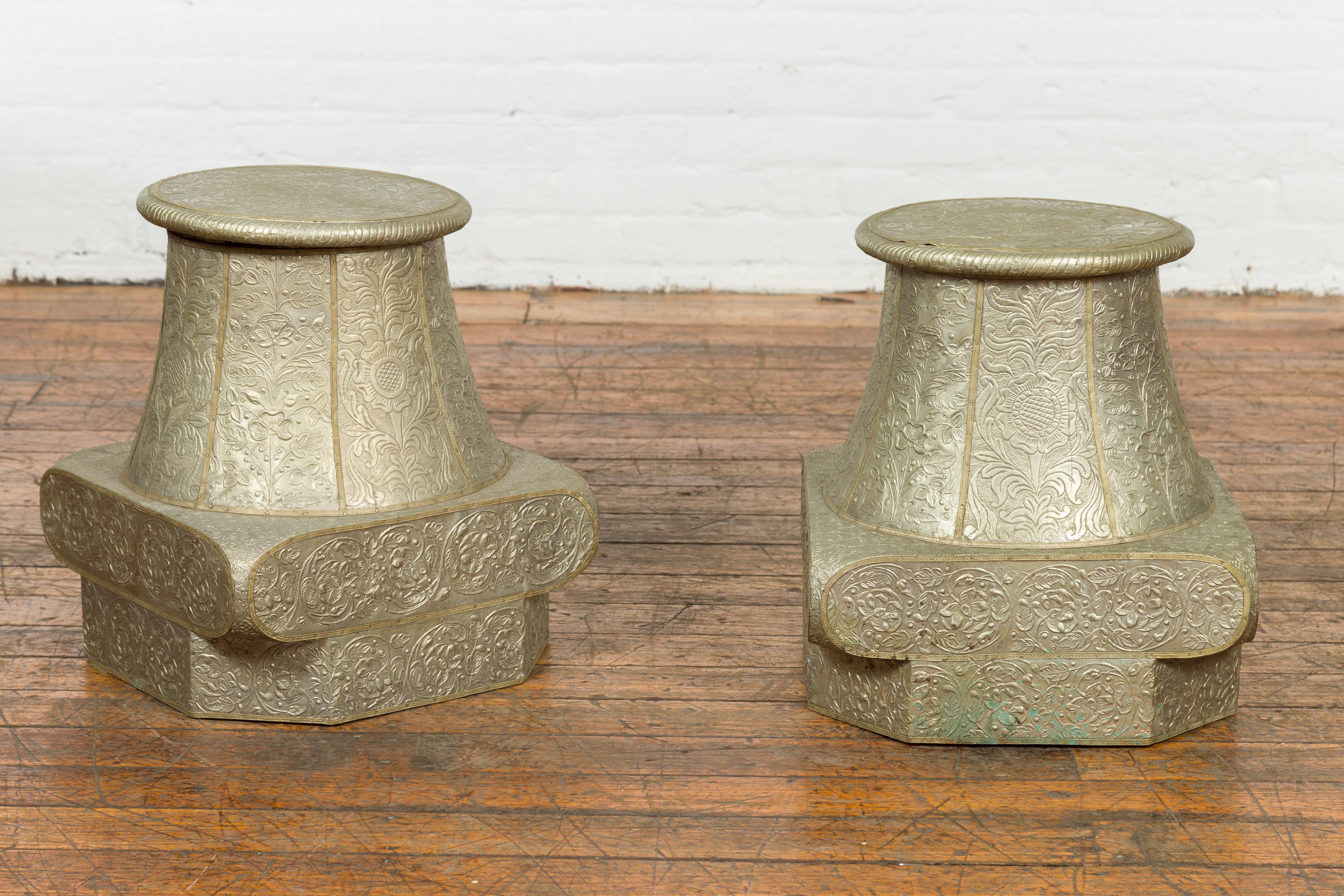 Two antique Indian brass over wood capital stands from the 19th century, with repoussé scrollwork décor. We are pricing and selling them each separately. Created in India during the 19th century, these pedestals showcase the shape of Classical