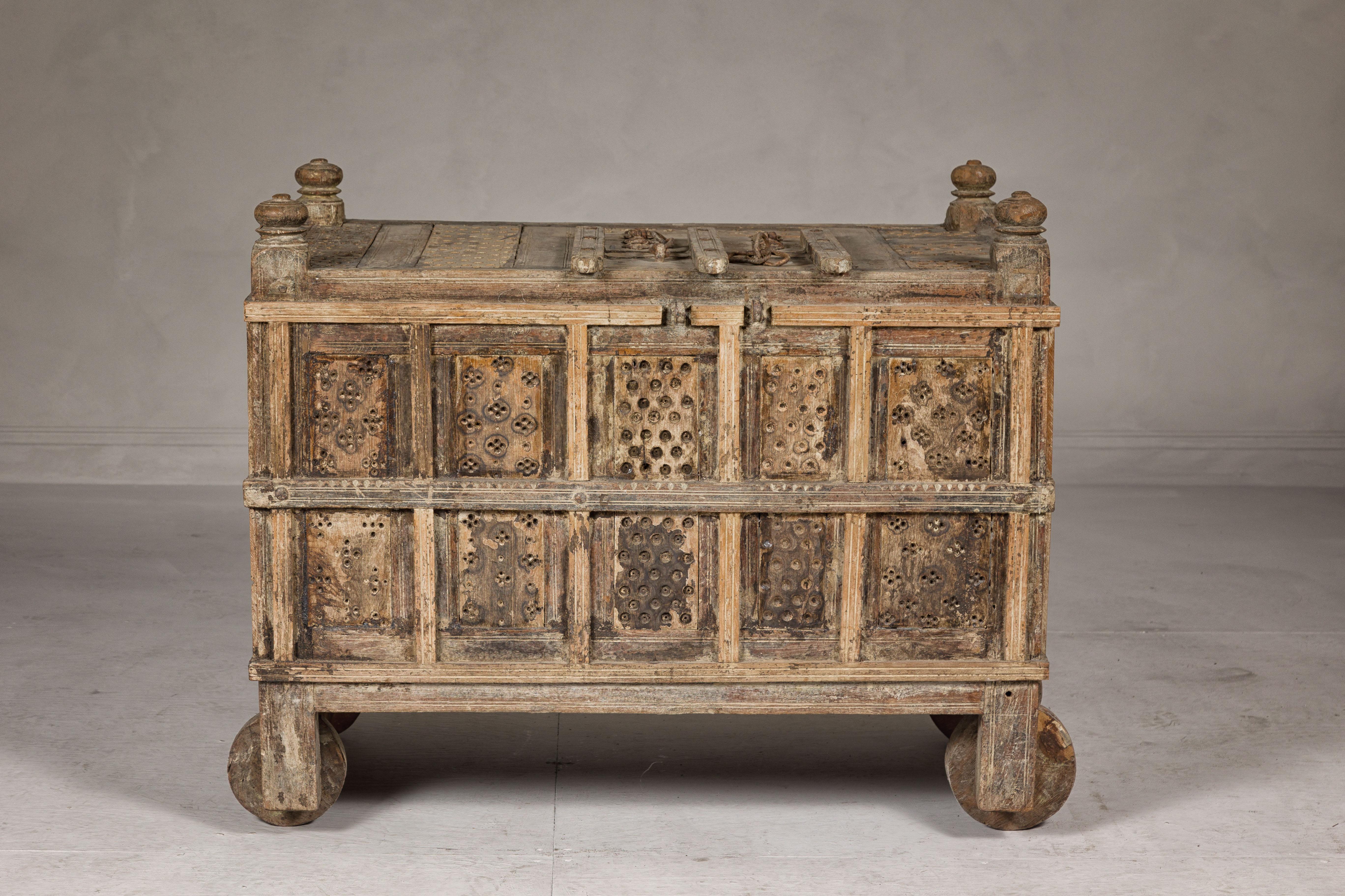An antique Indian Damachiya dowry cabinet on wheels with carved panels, turned finials and petite door on the top. This exquisite antique Indian Damachiya dowry cabinet, mounted on wheels for easy movement, is a testament to traditional