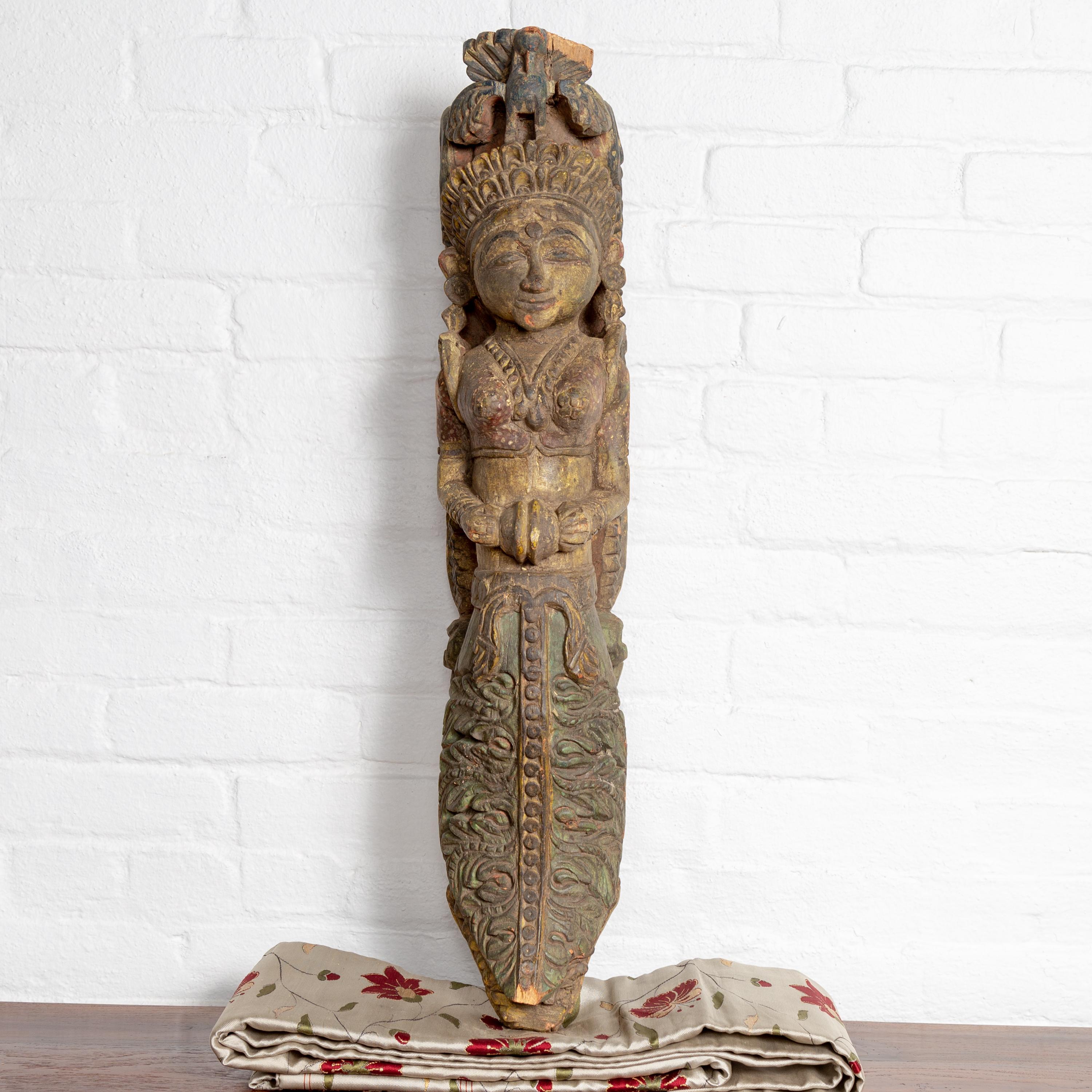 An antique Indian polychrome and hand carved wooden sculpture from the early 20th century, depicting a celestial musician playing an instrument. This captivating wooden sculpture beautifully captures the essence of celestial music through its