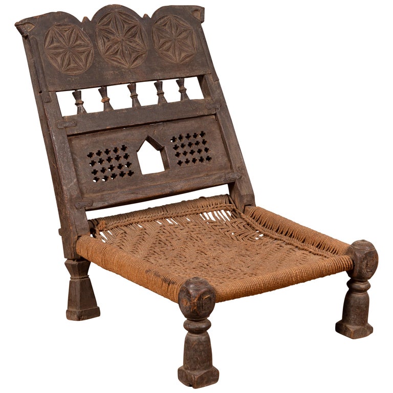 Chaise rustique indienne ancienne en bois à assise basse avec rosettes  sculptées et assise en corde En vente sur 1stDibs