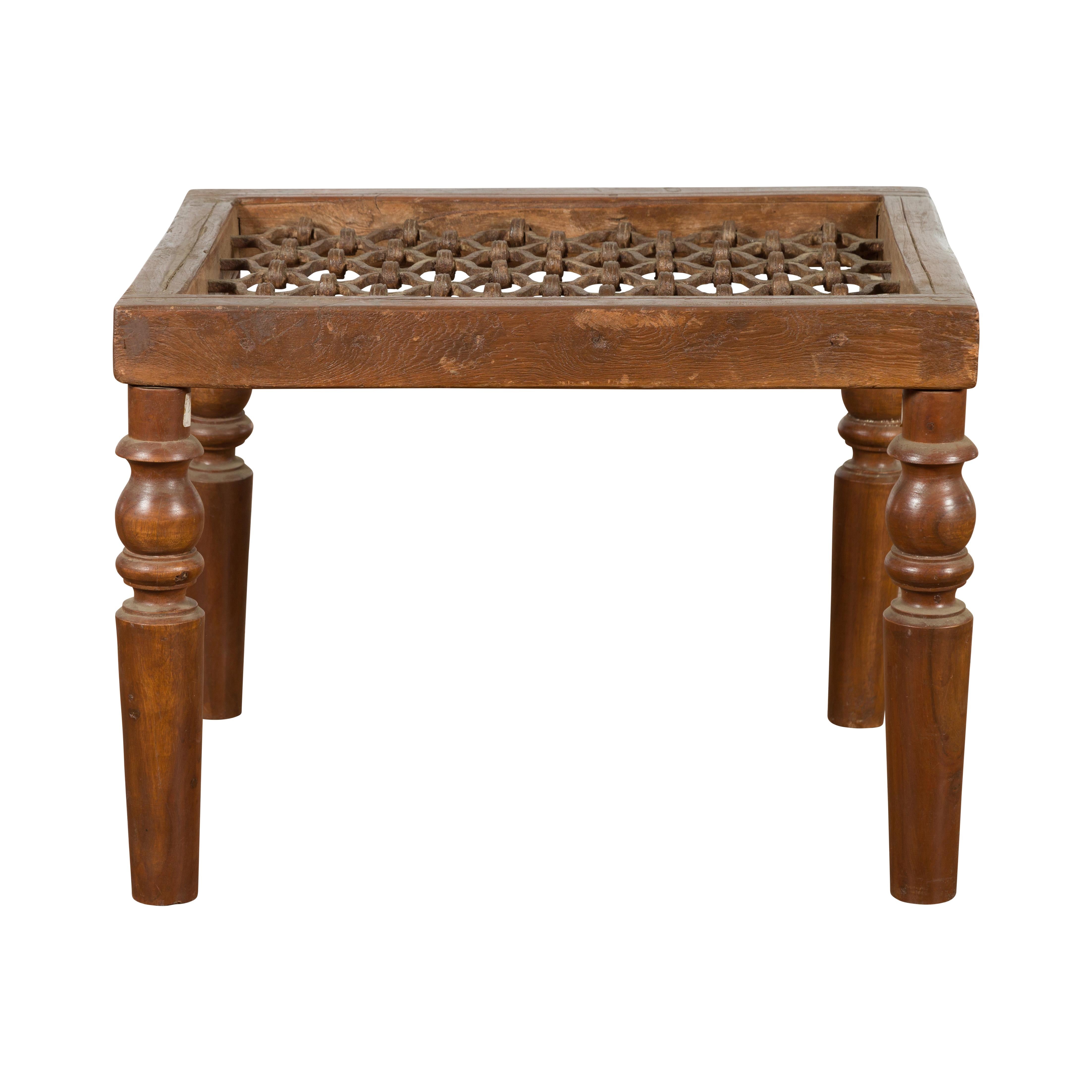 An antique rustic Indian window grate from the 19th century, made into a coffee table with baluster legs and weathered appearance. We have more assorted sizes available, please contact us with any questions. Created in India during the 19th century,