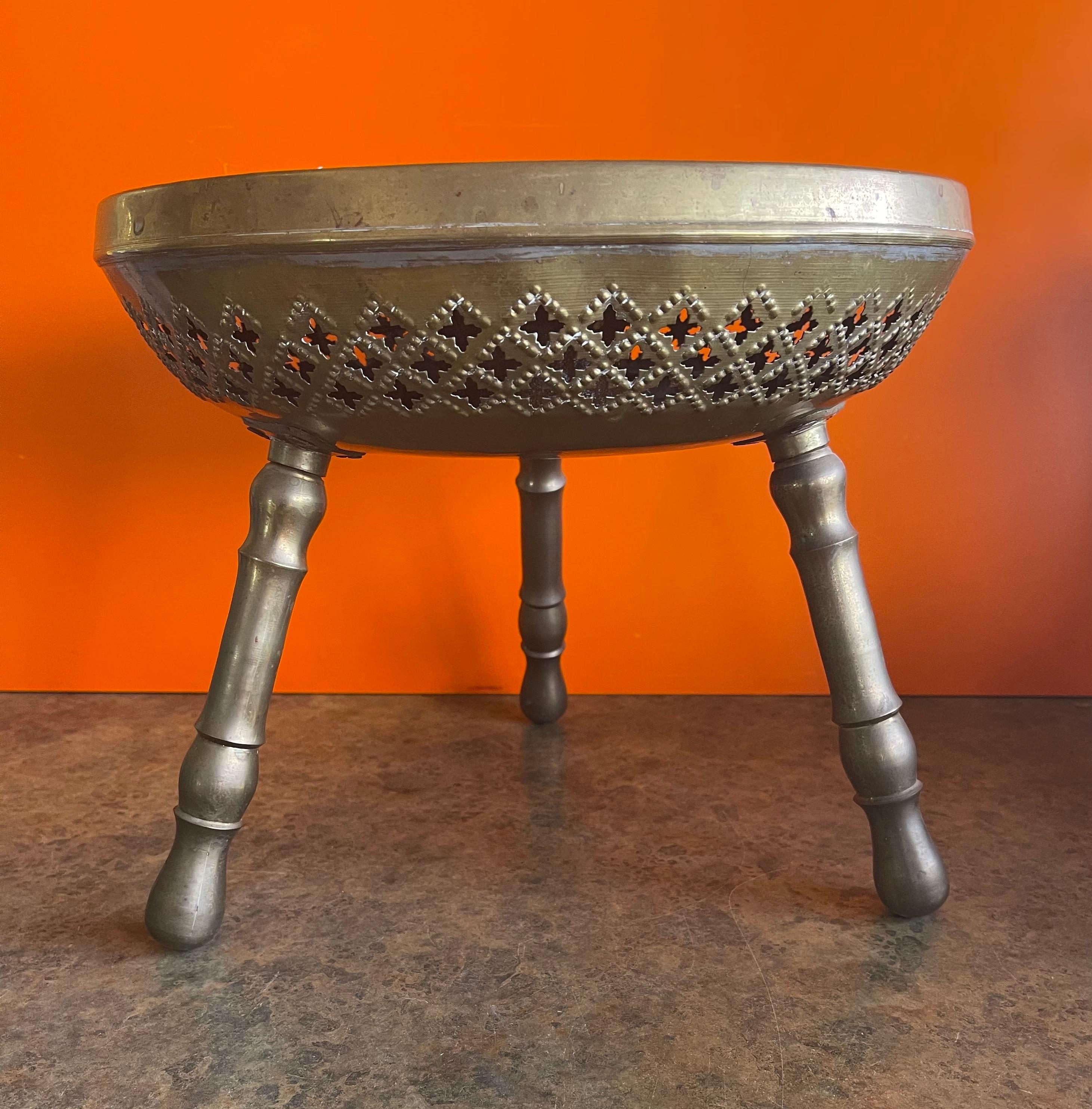 Indian brass three legged foot stool in brass, circa 1970s. Great patina finish and enscibed circular design in blue; Legs unscrew for easy storage. A very interesting, decorative and functional piece! #1489.