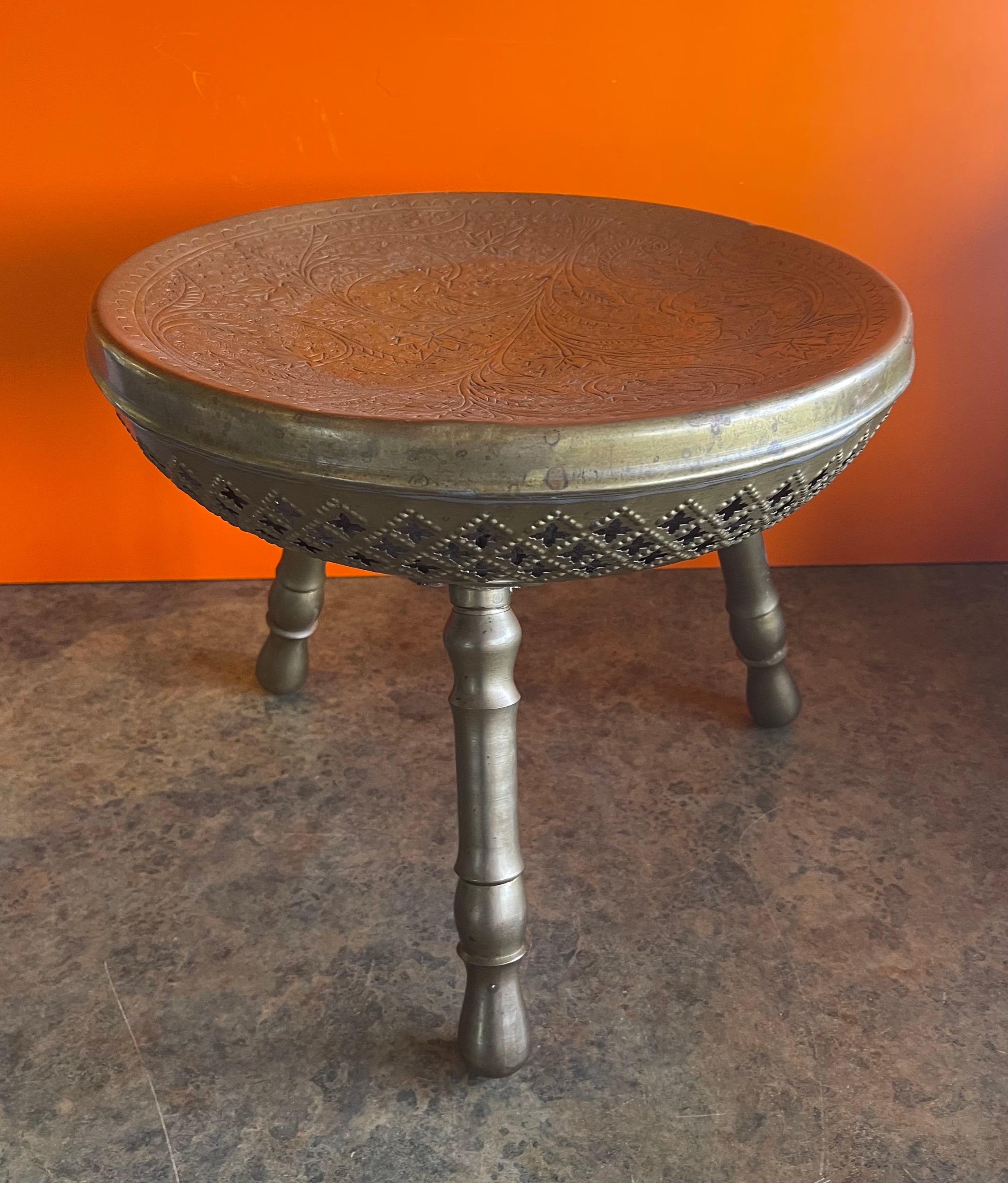 Indian brass three legged foot stool in brass, circa 1970s. Great patina finish and enscibed circular design; Legs unscrew for easy storage. A very interesting, decorative and functional piece! #1490.