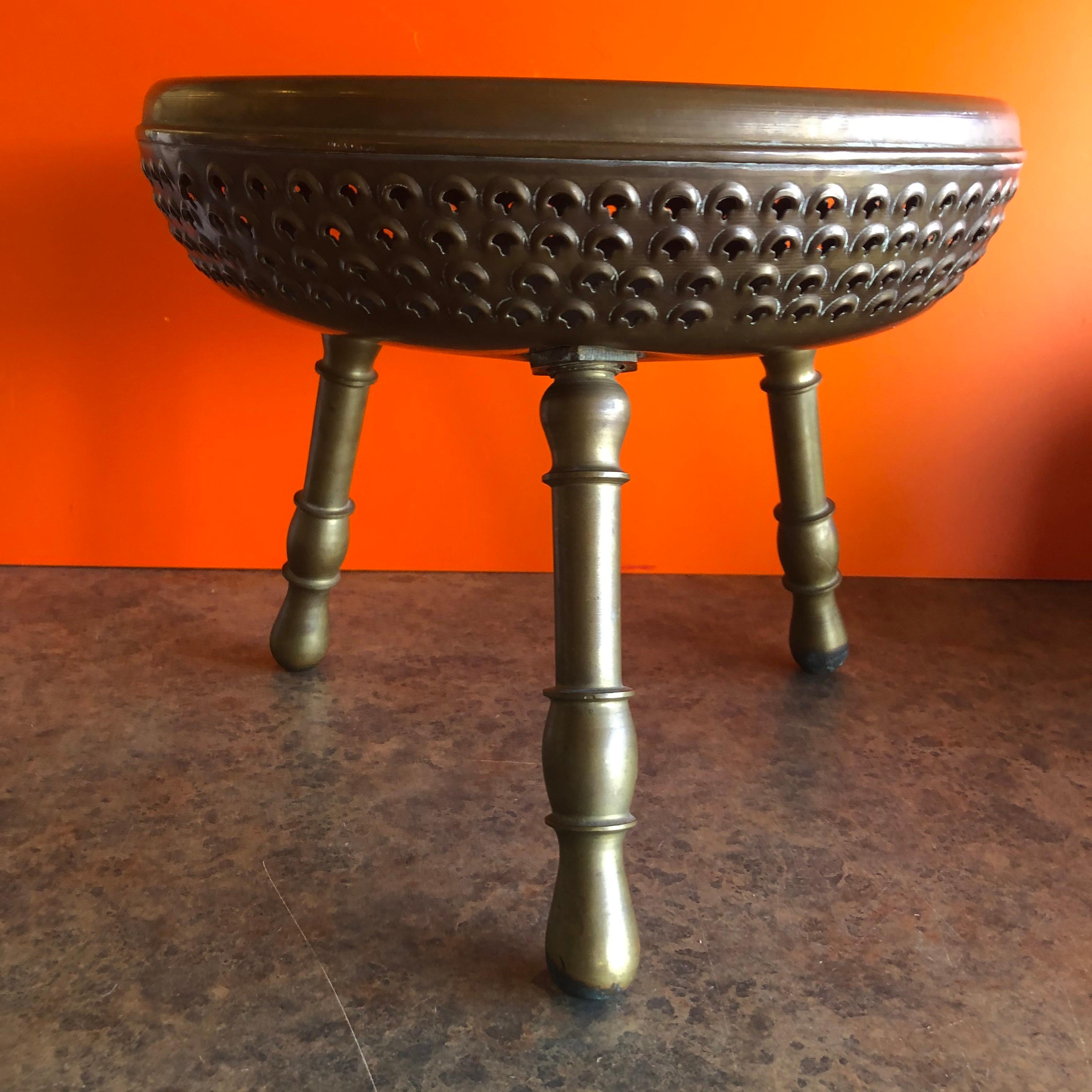 Indian brass three legged foot warmer / stool in brass, circa 1970s. Great patina finish and enscibed circular design; Legs unscrew for the fuel to be loaded and the stool to become a foot warmer. A very interesting, decorative and functional piece!