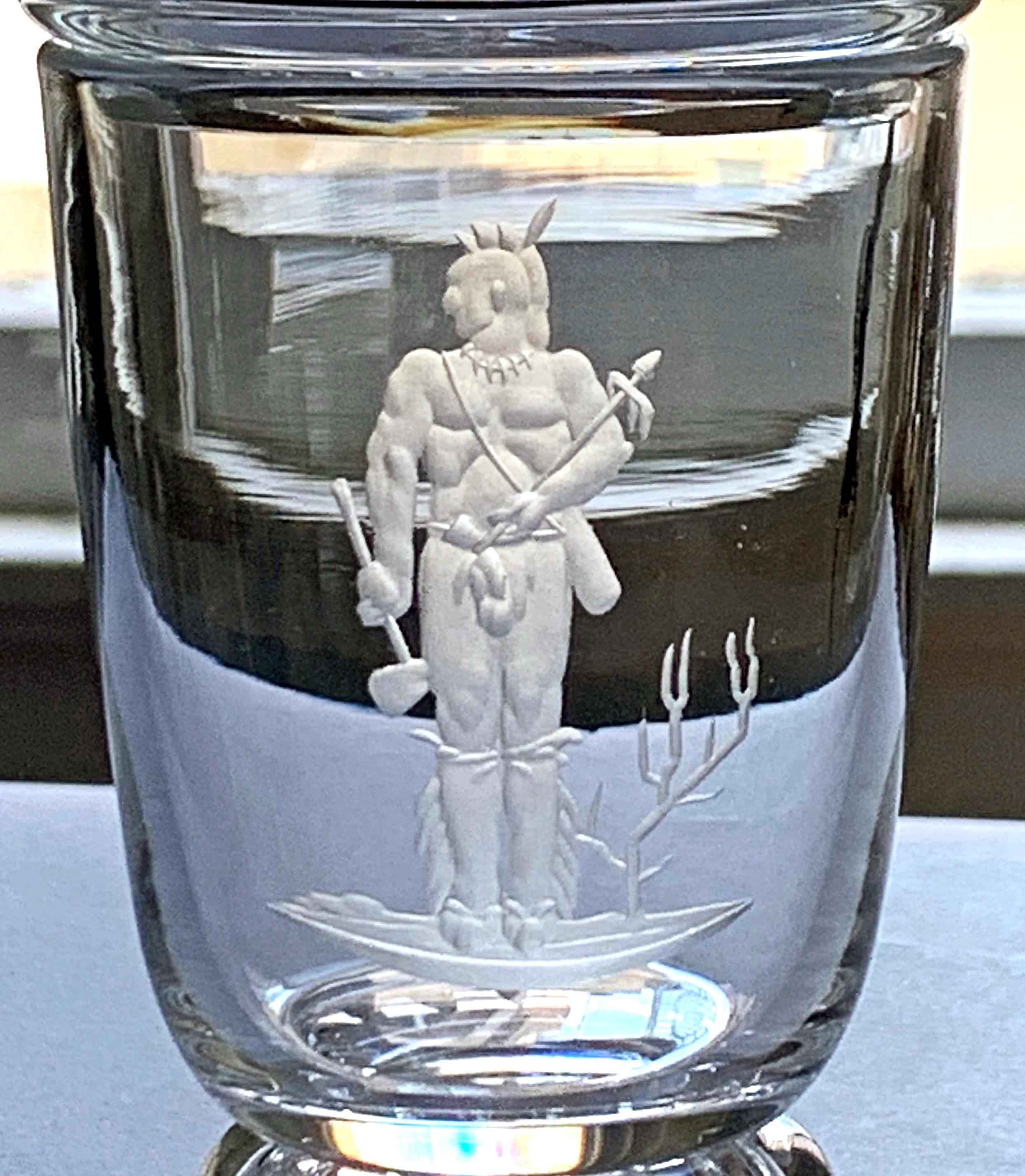 Designed by Sidney Waugh for the famed Steuben glass works, a part of the Corning Glass Company, this gorgeous, diminutive covered glass urn features a young Native American brave holding a peace pipe in one hand and a tomahawk in the other. Waugh