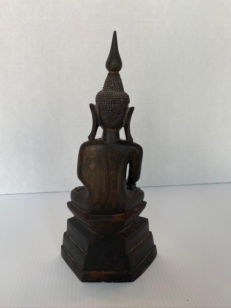 Indian Buddha Shan bronze sitting in lotus Pposition, 4 level step throne, eyes down, serene expression with prayer inside. Exquisite, well-defined detail. The right hand is poised with the fingertips downward and “touching the earth”, with the palm