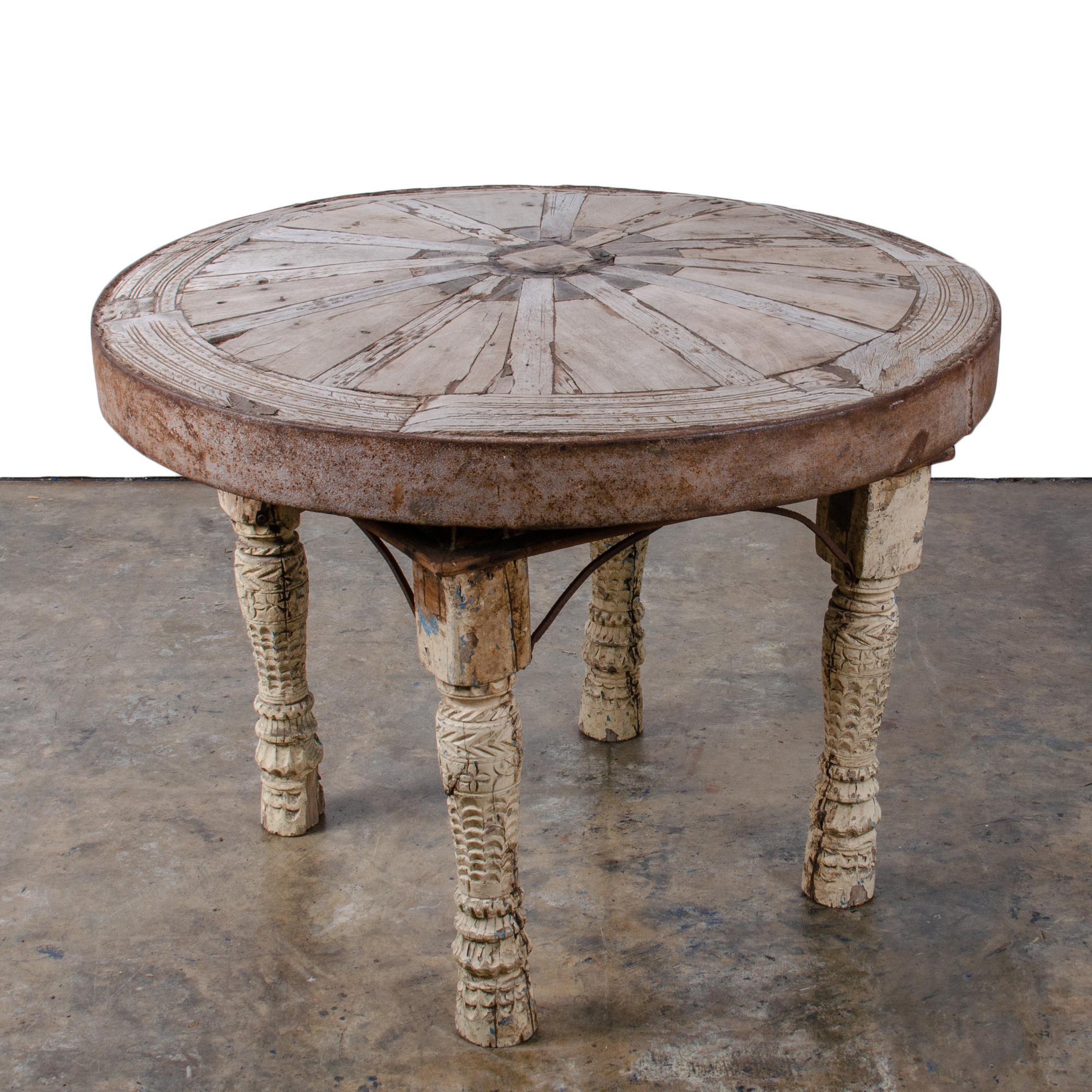 An antique Indian bullock cart wheel with iron tread mounted as a table on carved painted legs with iron bracing.  

34 inches wide by 33 inches deep by 24 inches tall

