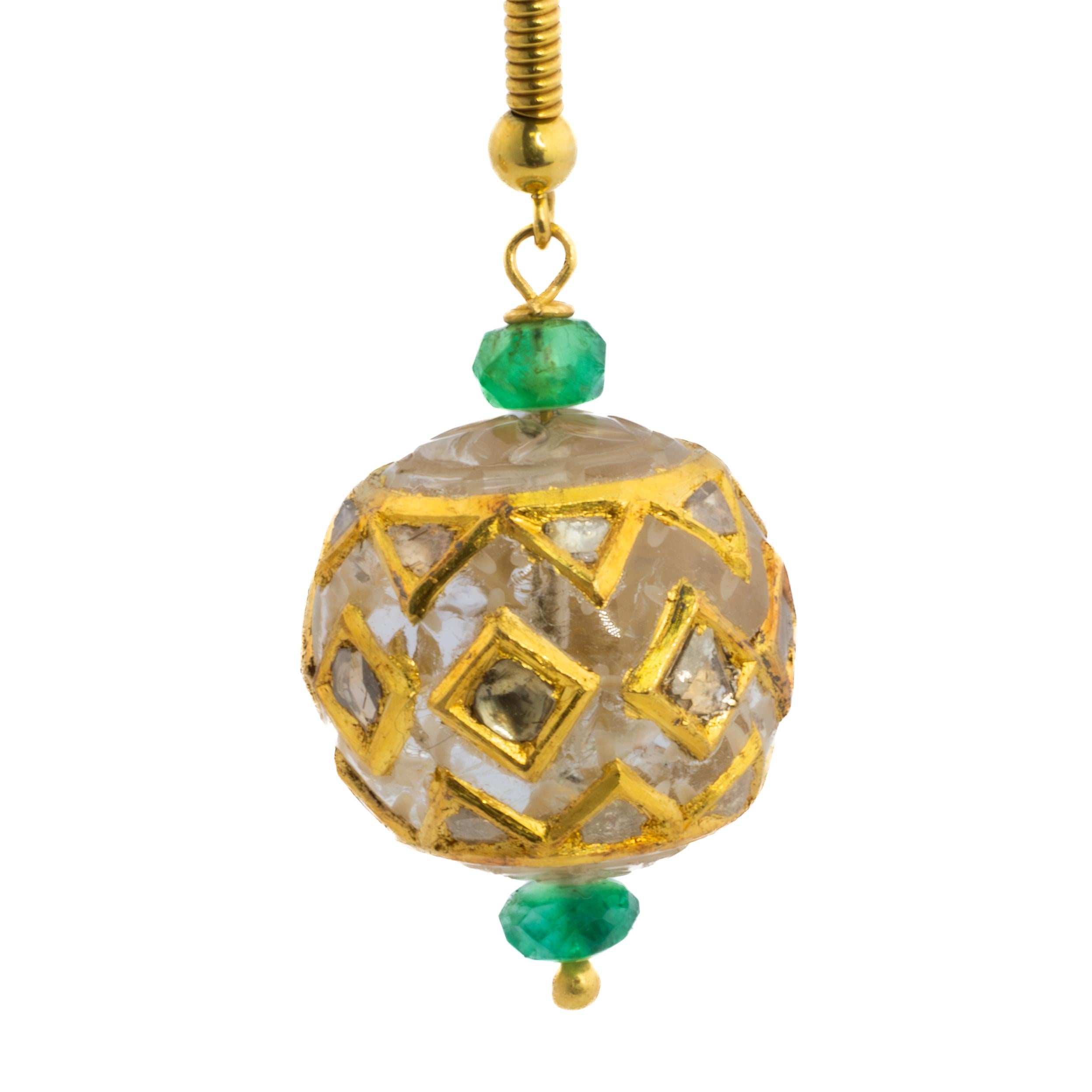 Indian Carved Rock Crystal and Emerald Bead Earrings

Description:
A pair of artisanal earrings crafted in 14 karat yellow gold, featuring intricately carved rock crystal beads accented with gold diamond-shaped details. Each bead is further adorned