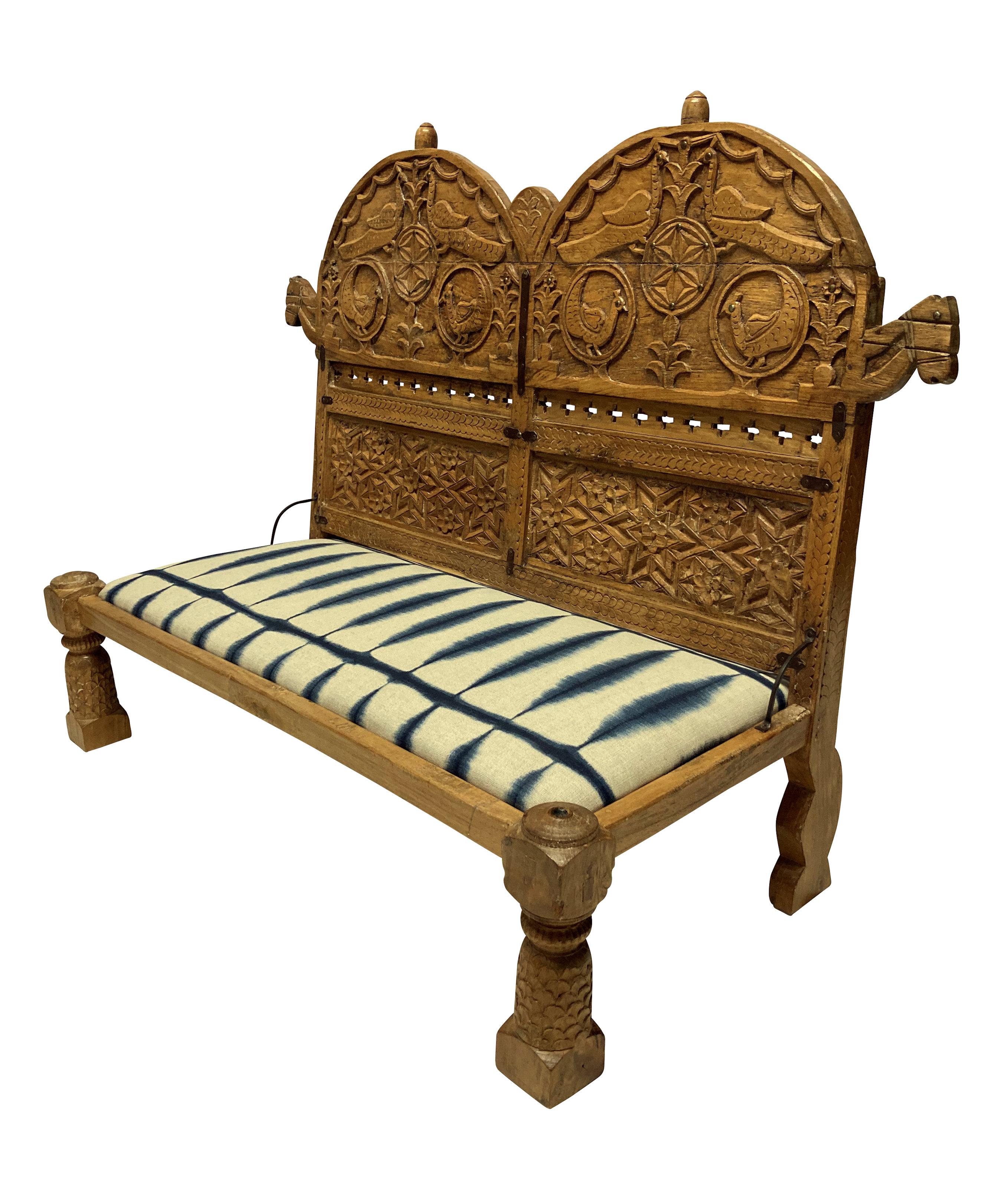 An Indian ornately carved teak floor seat, with peacocks and foliage. Newly upholstered in linen.
